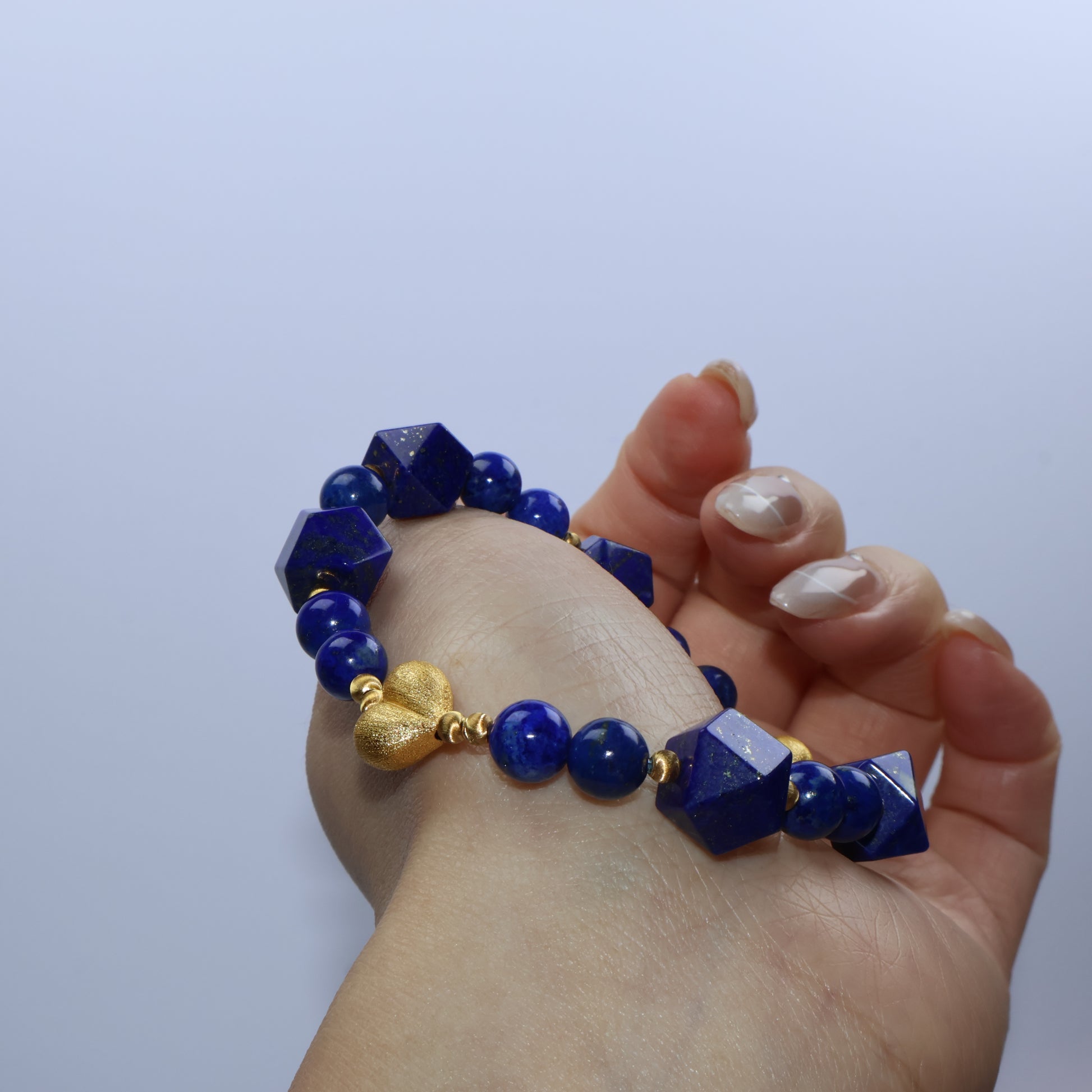 Close-up of heart-shaped gold-plated silver charm and deep royal blue lapis beads