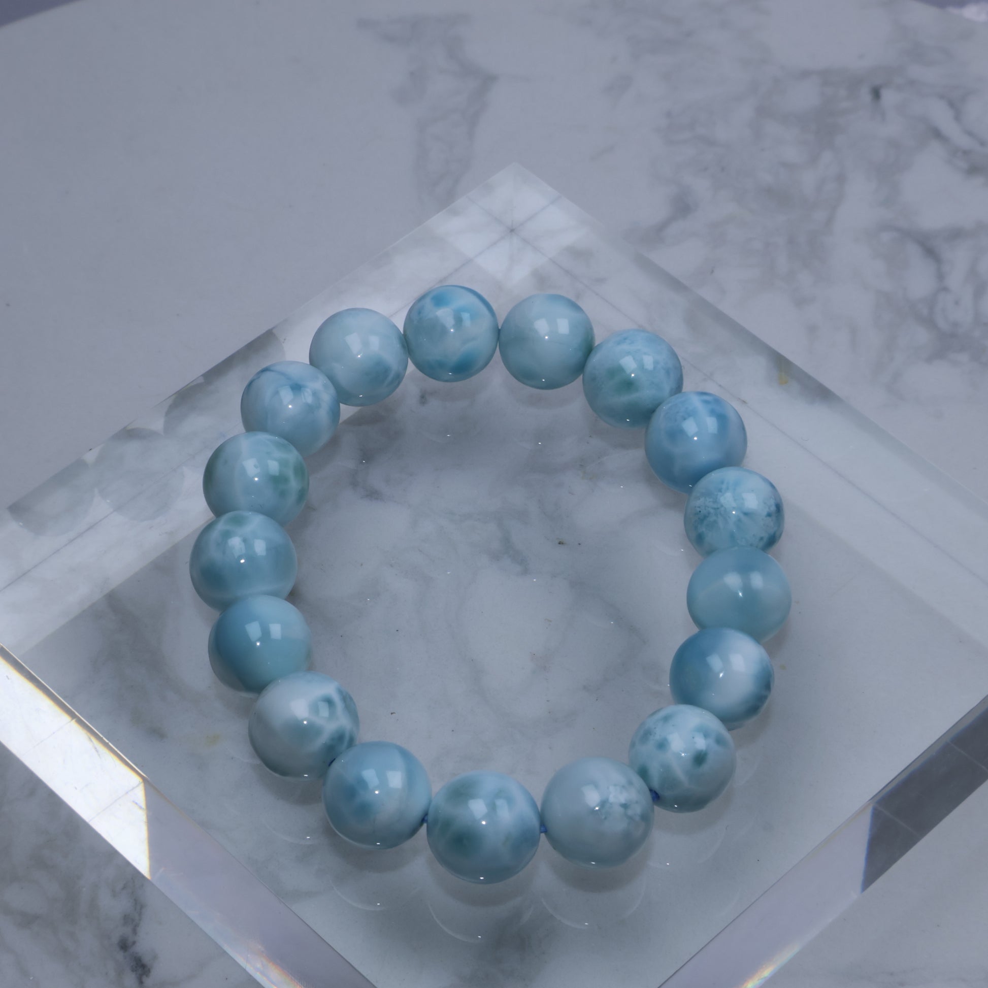 Flat lay of Larimar bracelet on clear acrylic block showing smooth, glossy finish