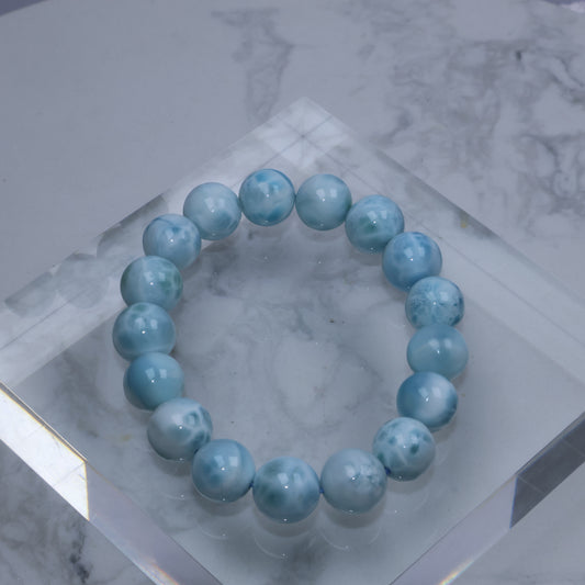Flat lay of Larimar bracelet on clear acrylic block showing smooth, glossy finish