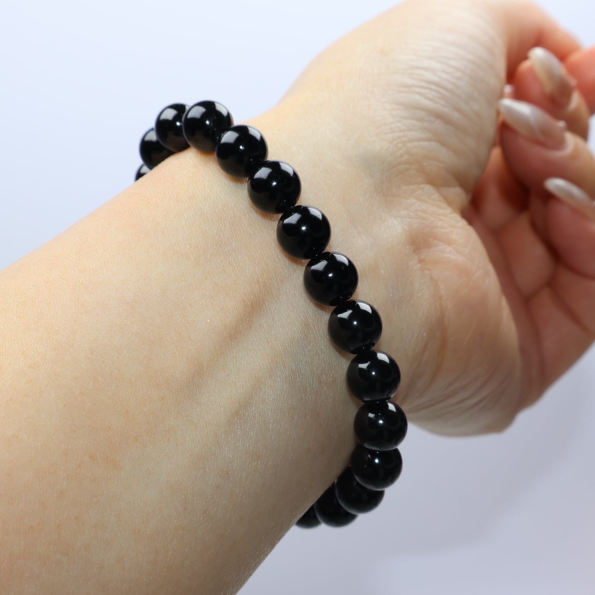 Angle view of bracelet worn on wrist, emphasizing the deep black shine of the beads