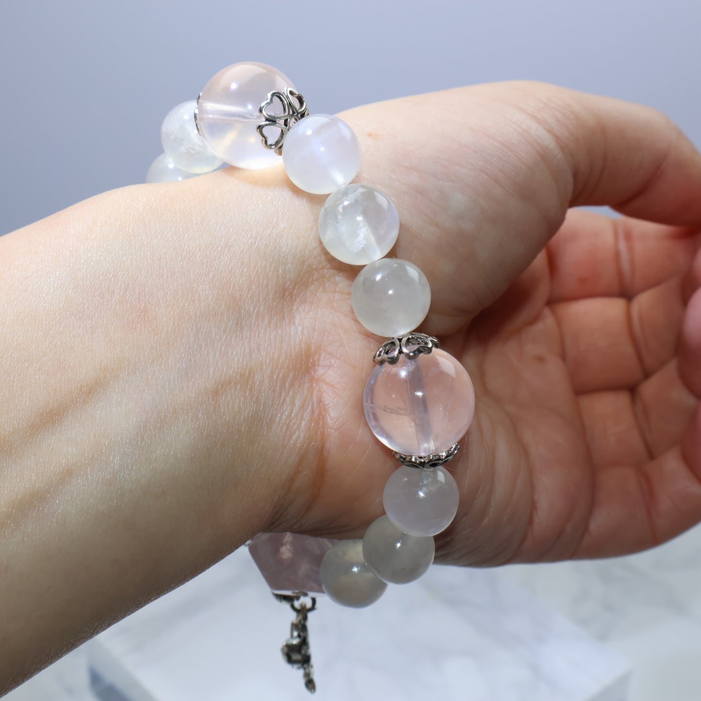 Mystic Key Original moonstone & rose quartz bracelet with fox charm, worn on hand
