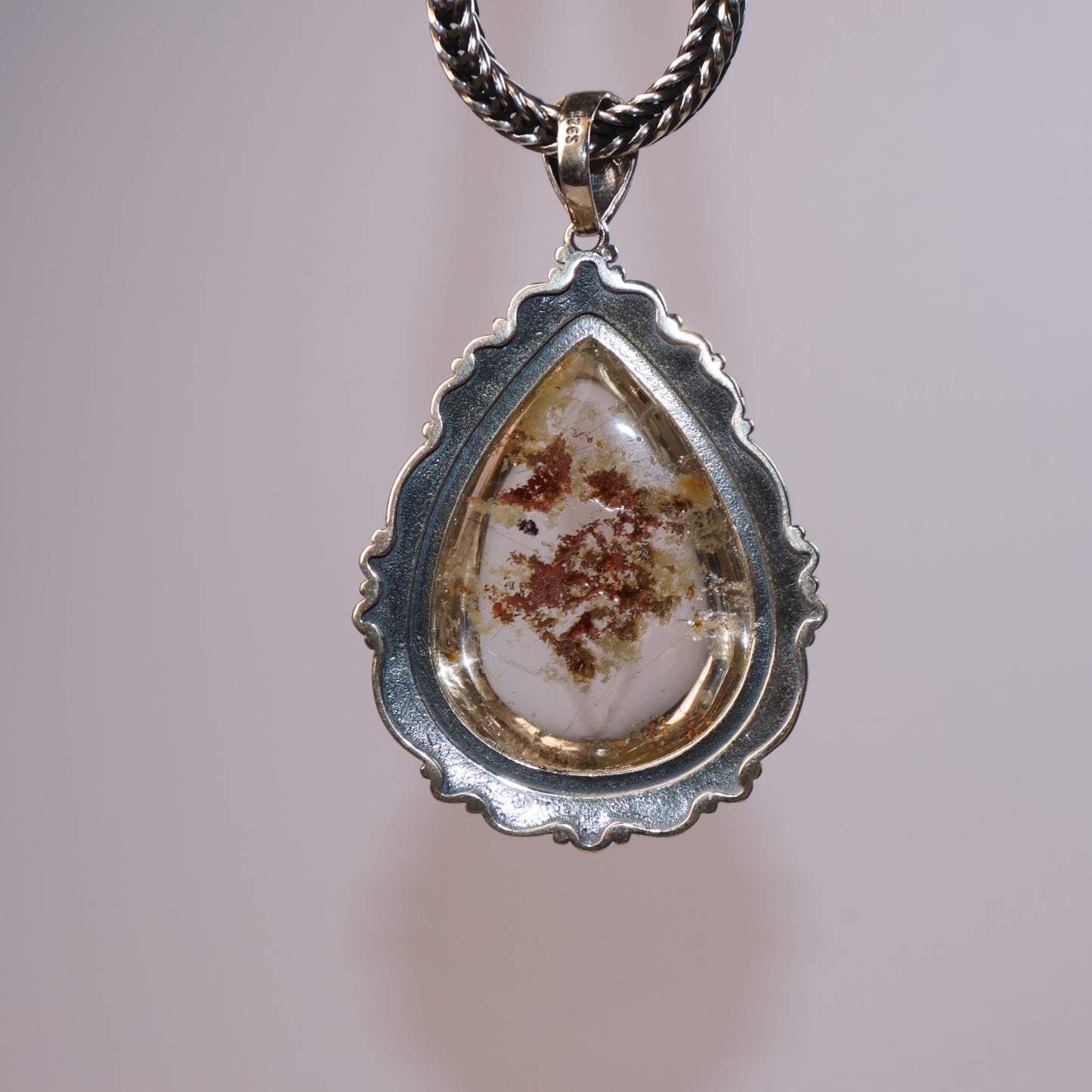 Back view of teardrop Phantom Quartz pendant showing natural inclusions and silver bezel setting in a scalloped design.