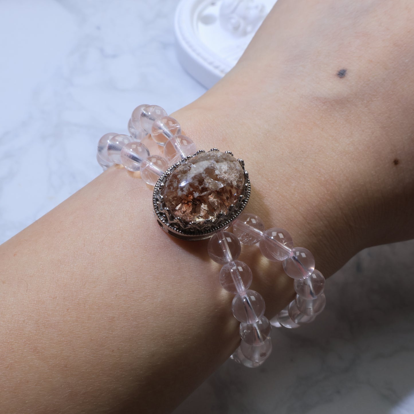 Bracelet worn on wrist, displaying balance between Phantom Quartz centerpiece and Rose Quartz strands