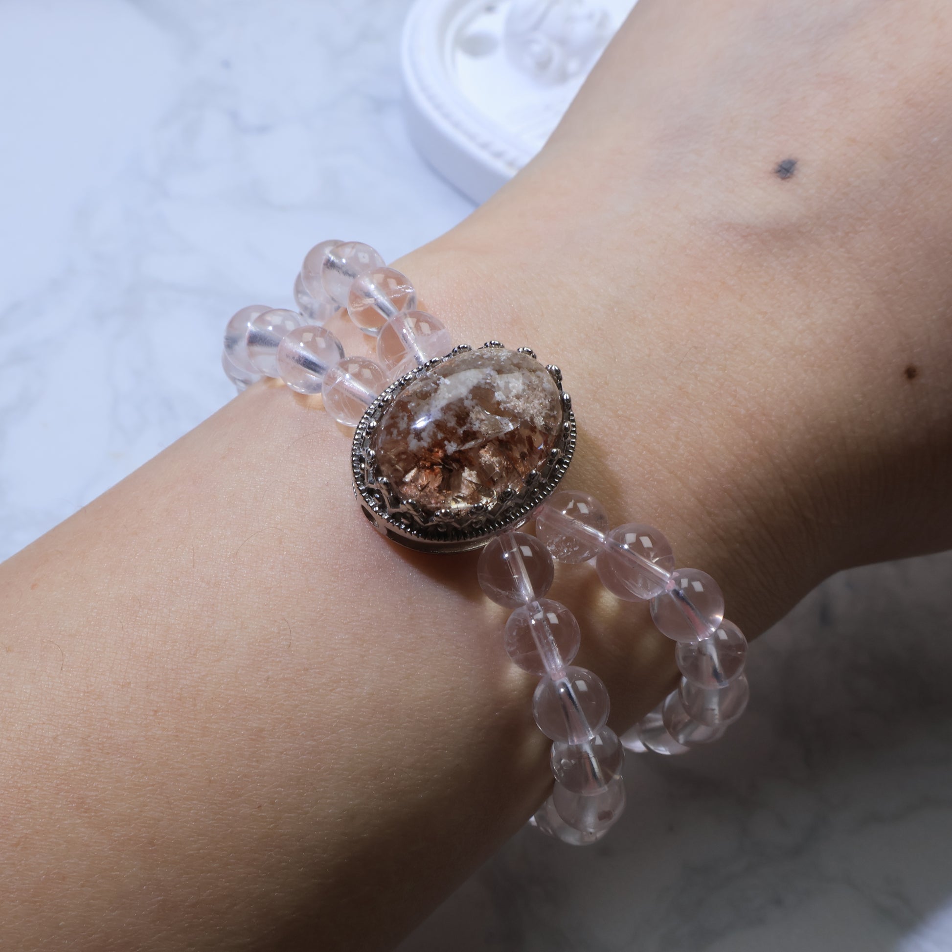 Bracelet worn on wrist, displaying balance between Phantom Quartz centerpiece and Rose Quartz strands