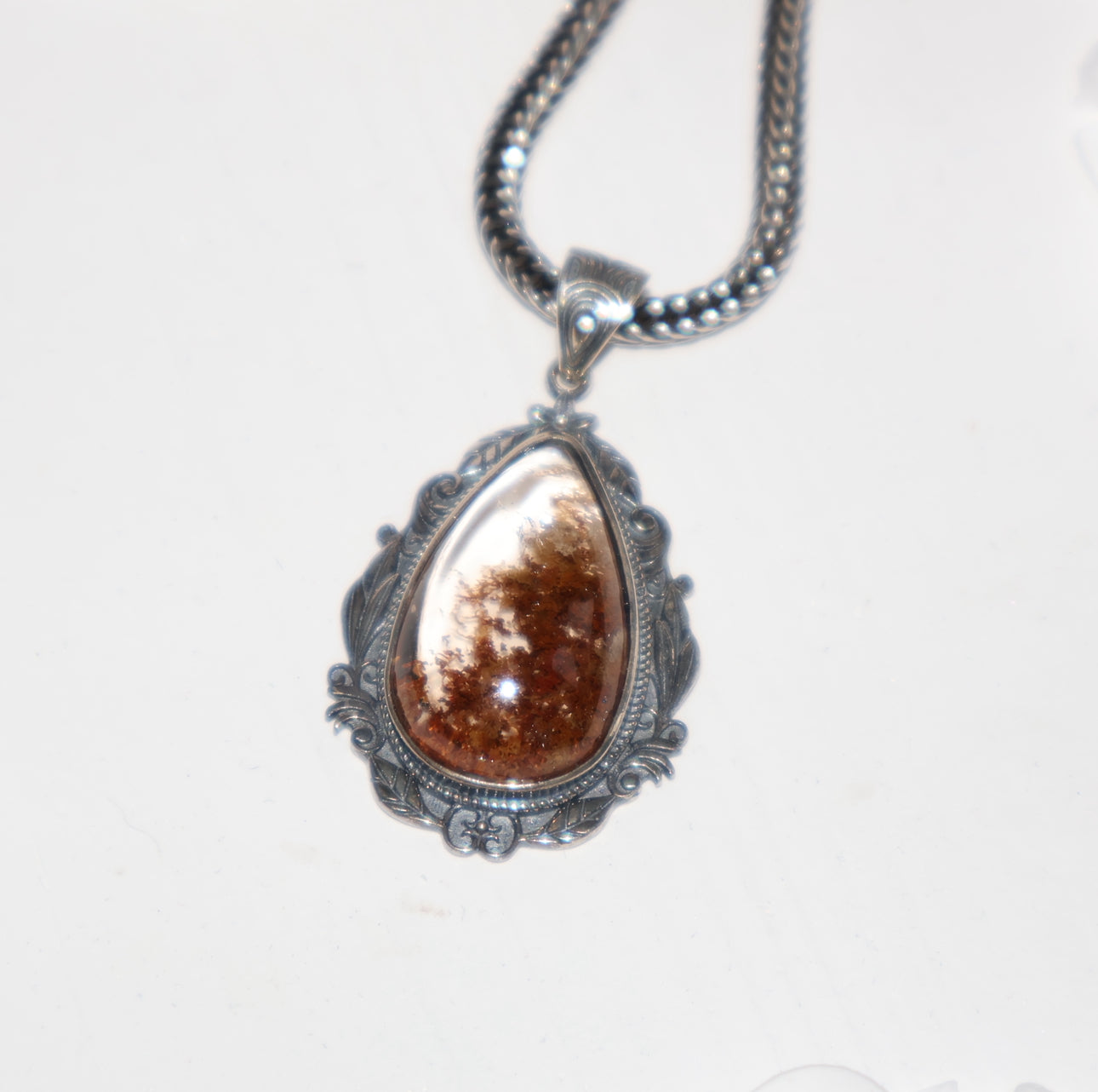 Close-up of Phantom Quartz pendant with reddish-brown inclusions in ornate S925 silver setting