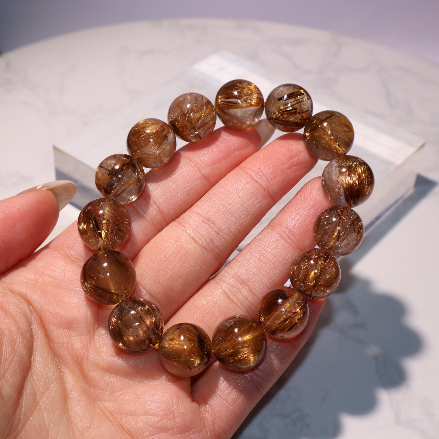 Rutilated quartz bracelet viewed across fingers to showcase clarity and luster