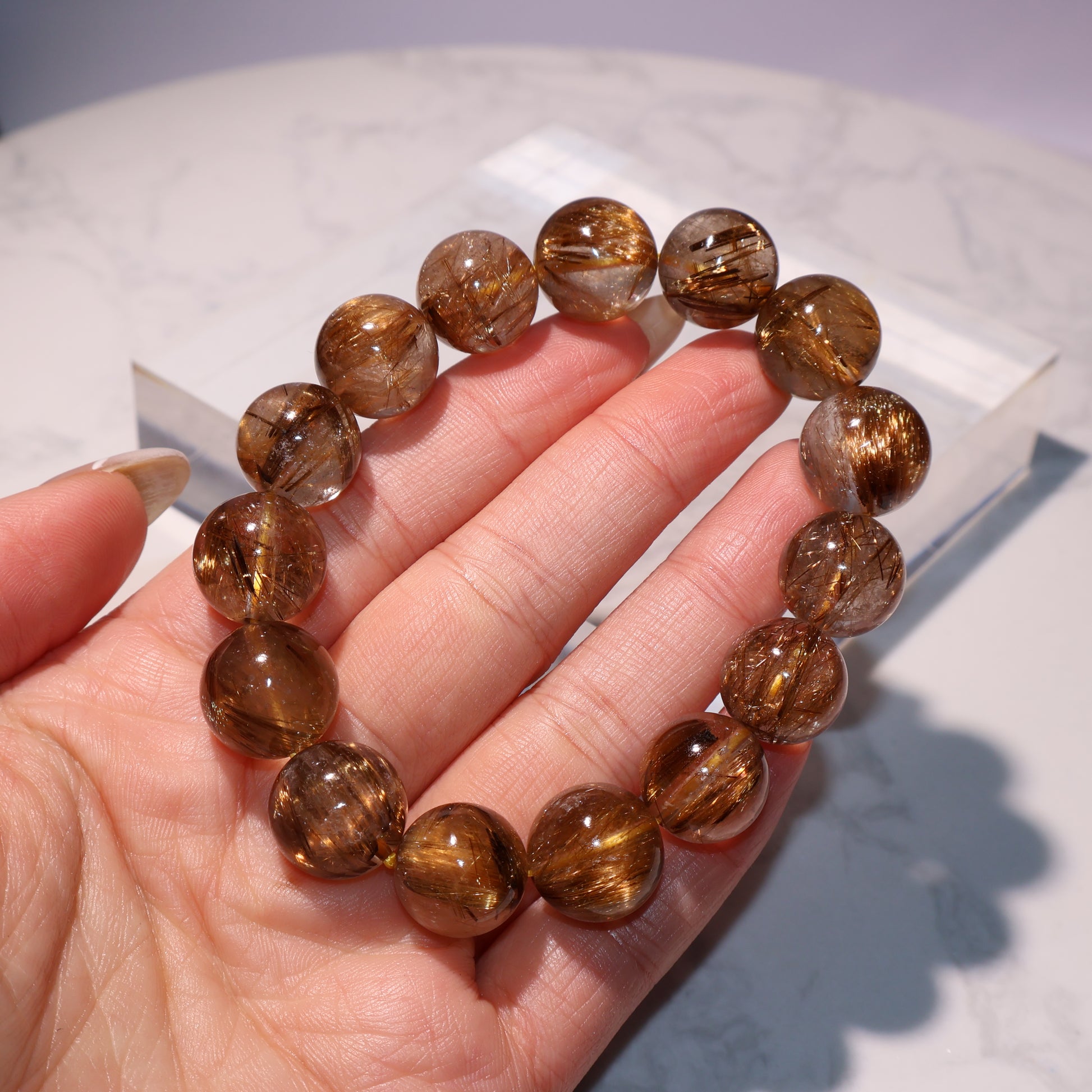 Rutilated quartz bracelet viewed across fingers to showcase clarity and luster