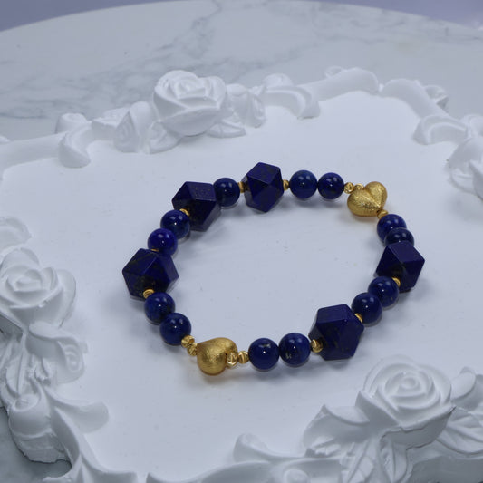 Top-down photo of blue and gold crystal bracelet placed on ornate white rose display
