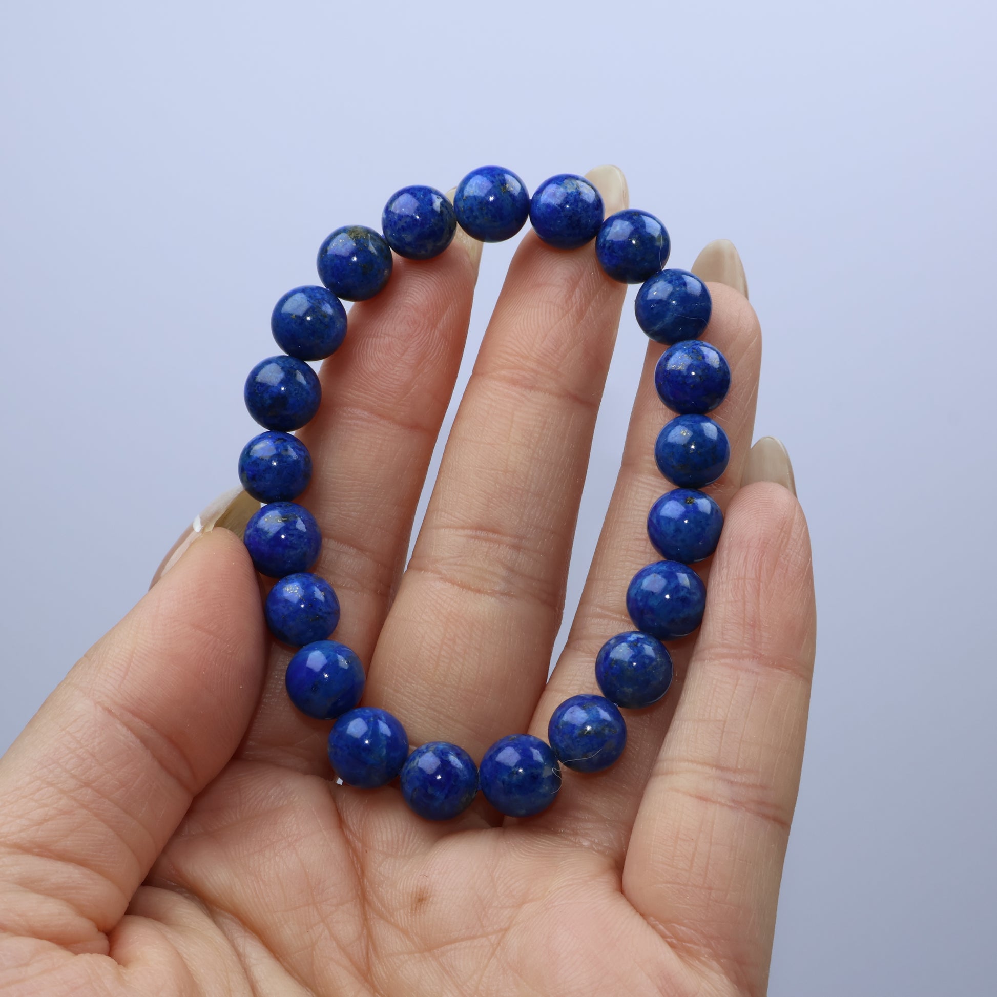 Handheld view of Lapis Lazuli bracelet showing deep royal blue beads with subtle pyrite specks