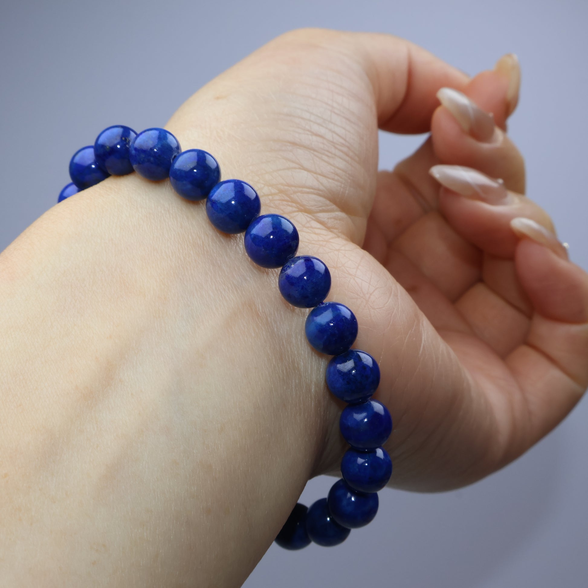 Over-hand photo displaying the Lapis Lazuli bracelet in a natural pose with fingers gently 