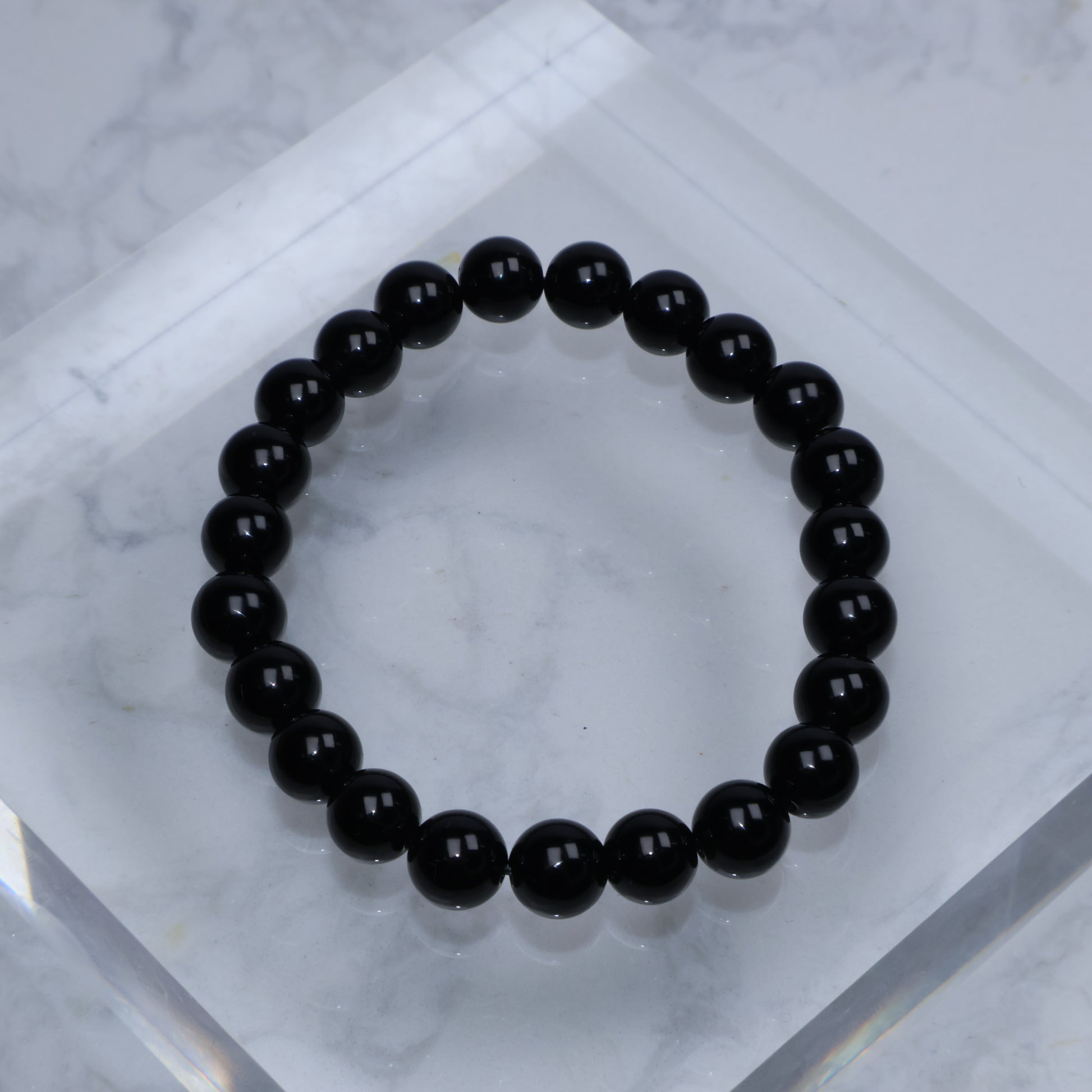 Top-down view of polished Black Tourmaline bracelet arranged in a circle on marble block