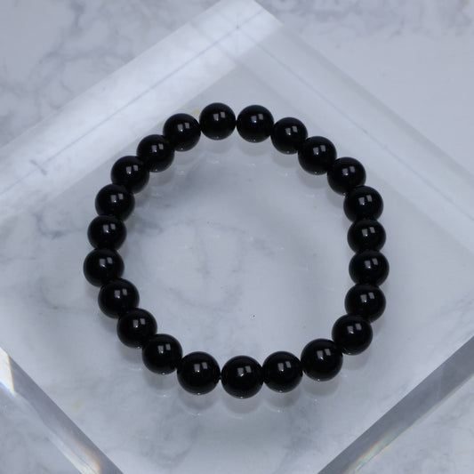 Top-down view of polished Black Tourmaline bracelet arranged in a circle on marble block