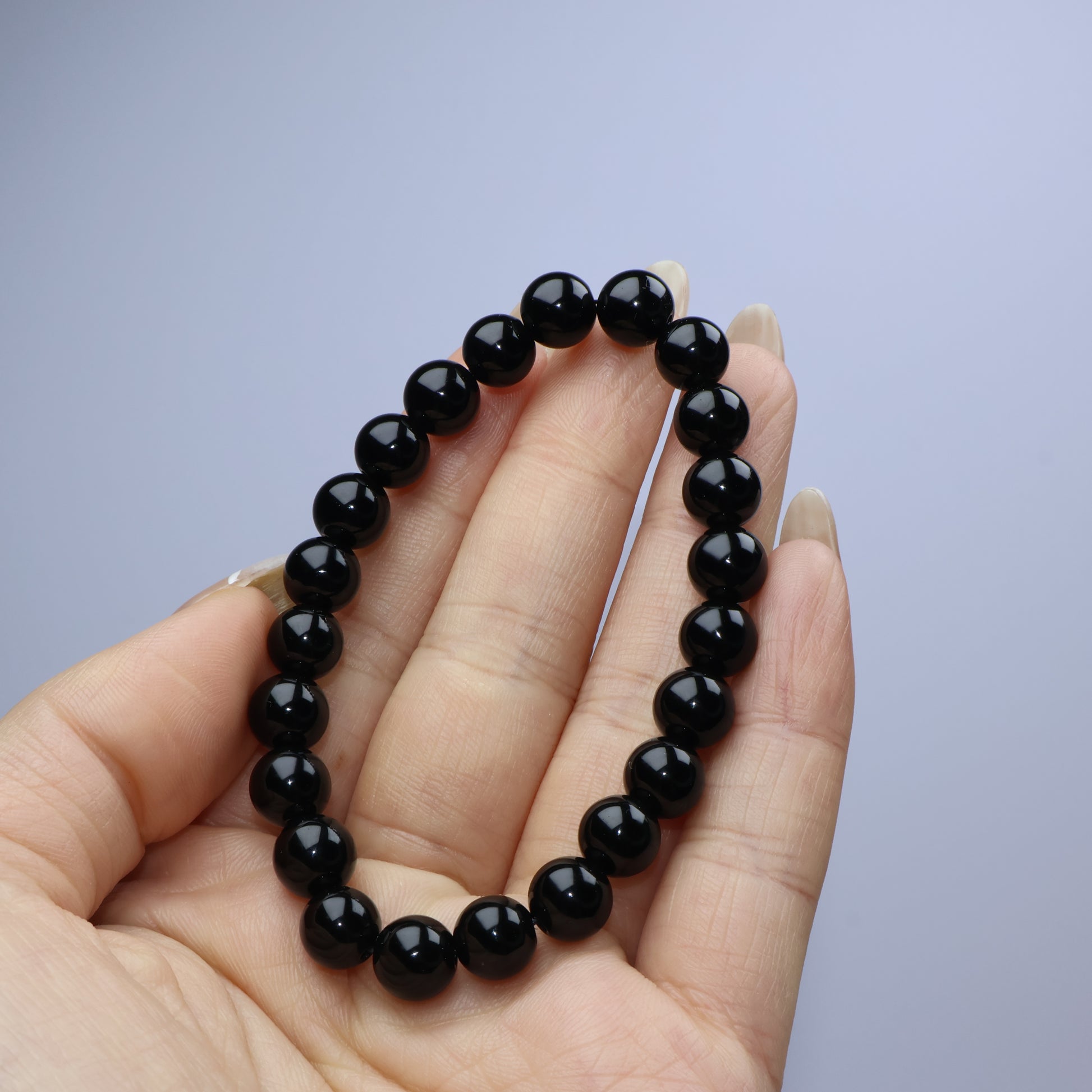 Handheld view showing 8 mm uniform black beads with glossy finish