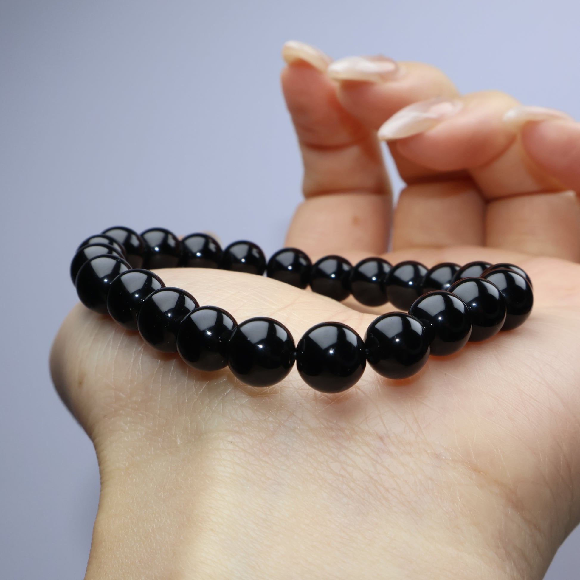 Bracelet curved over back of hand highlighting bead luster and deep color