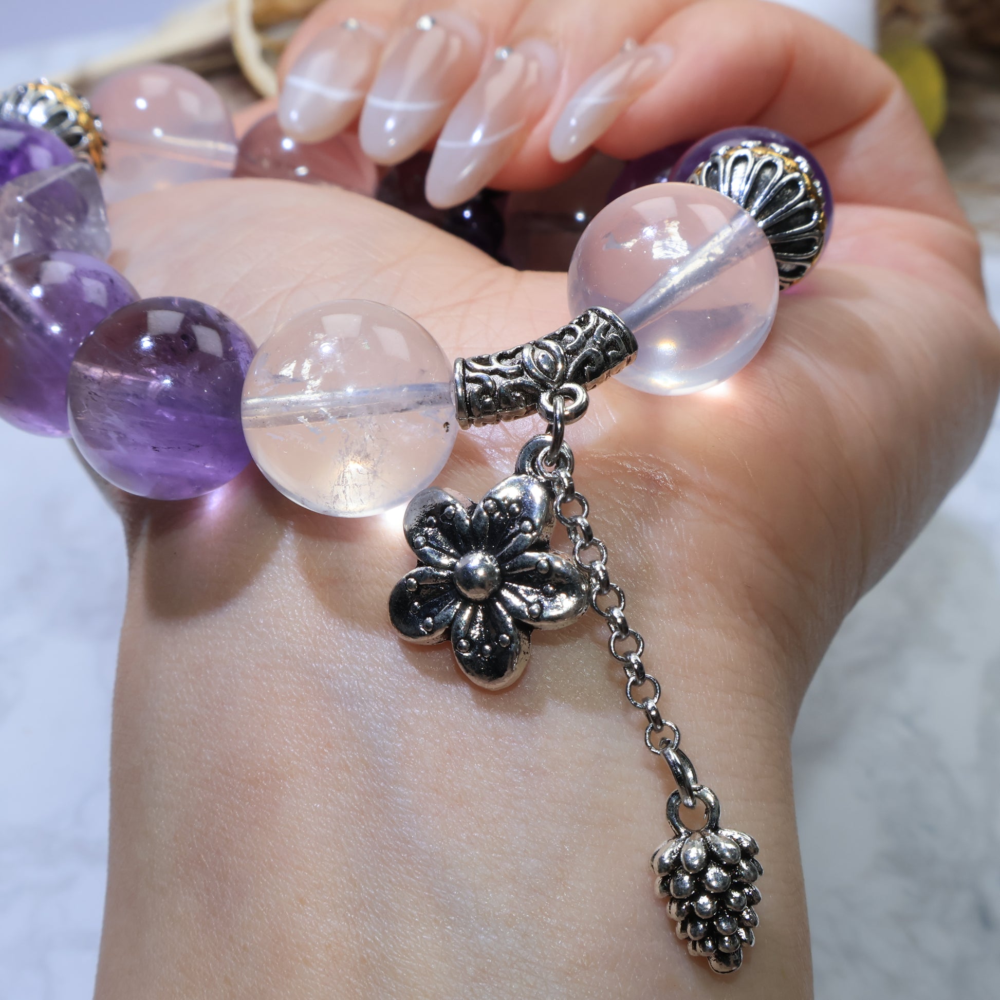 Macro of the copper bail and chain charms beside 15 mm rose quartz and amethyst beads.