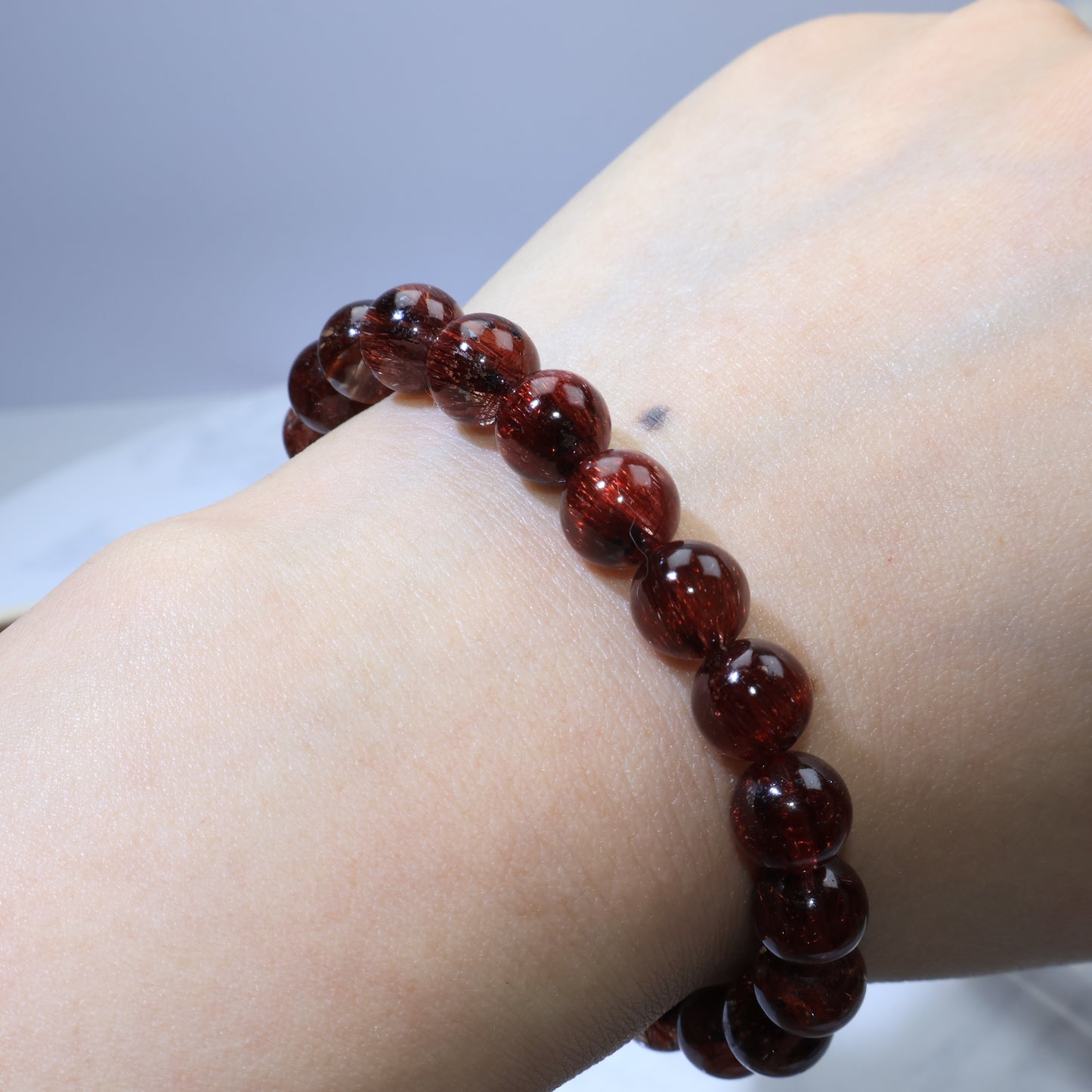 Wrist shot—artificial lighting reflecting off the transparent Red Rutilated Quartz
