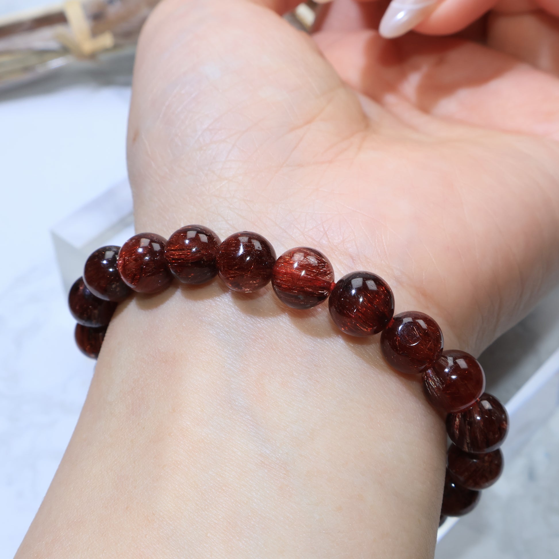 Close wrist view of Red Rutilated Quartz beads arranged in a smooth loop