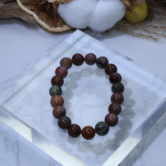 Top view of 9mm Alxa Agate bracelet on clear acrylic display, showing mix of earthy tones
