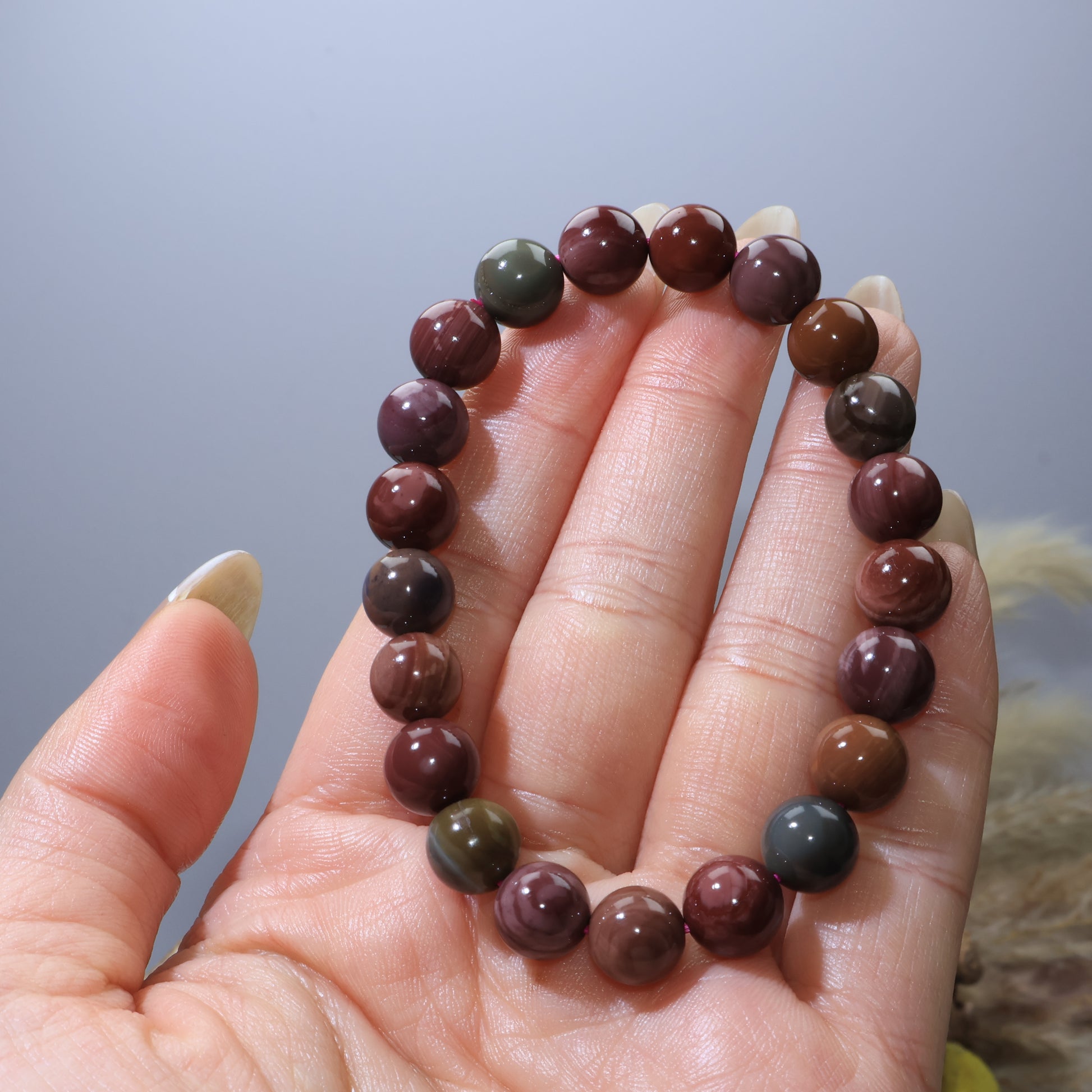 Hand holding Alashan Agate bracelet showing earthy tones