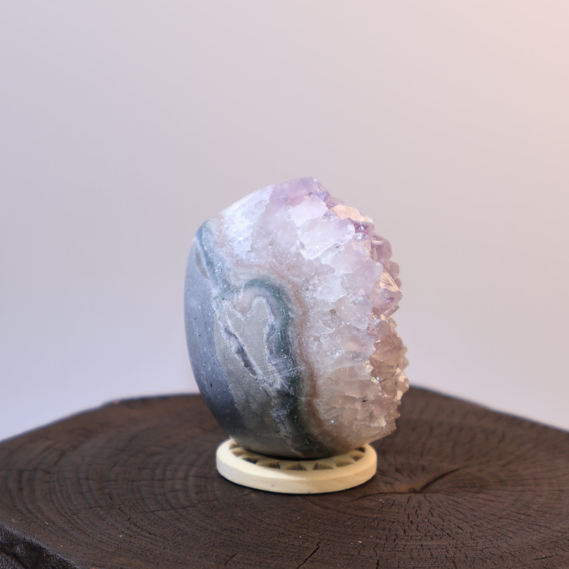 Side view of Amethyst egg with natural banding and exposed crystals.