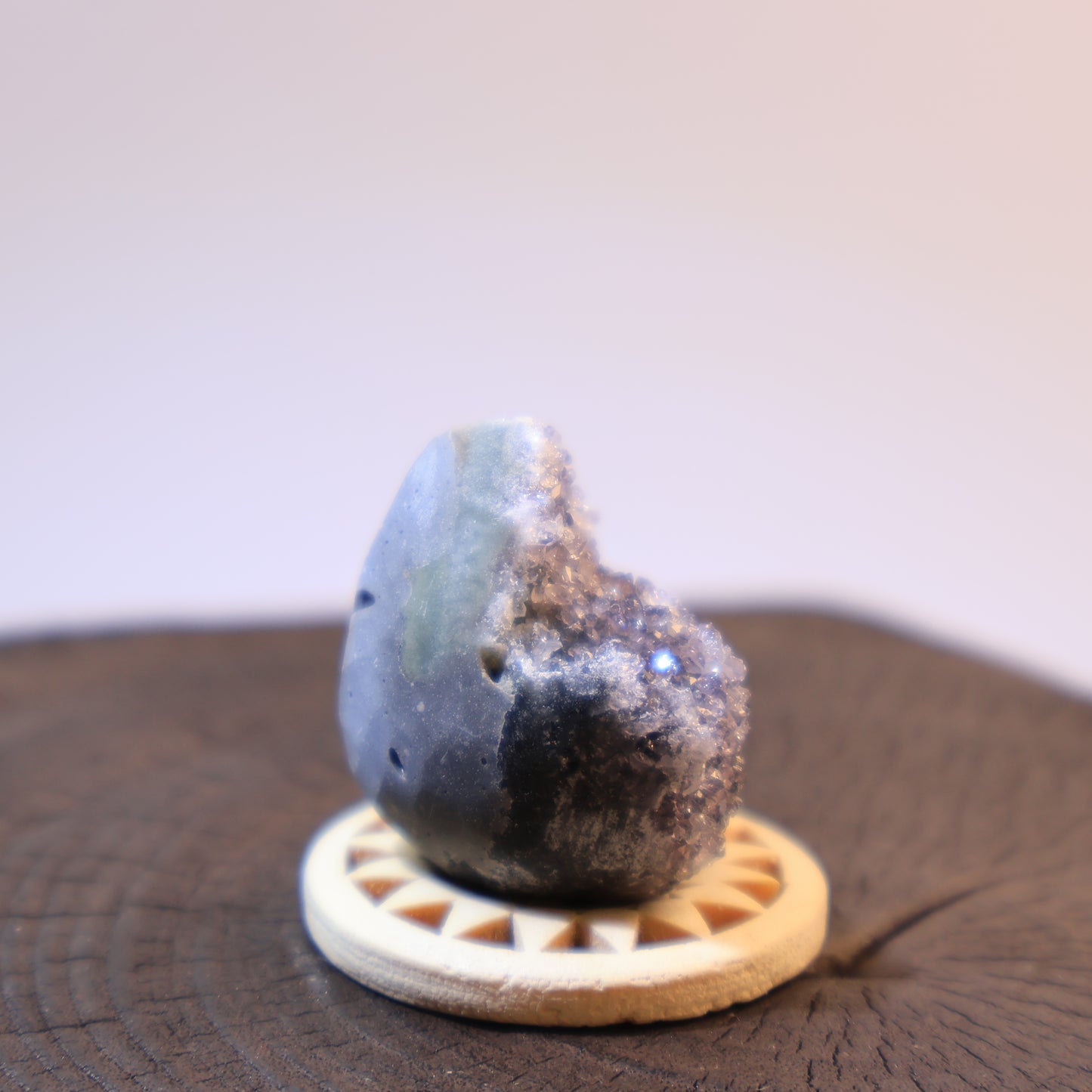 Side view of grey quartz geode egg showing exposed crystals.