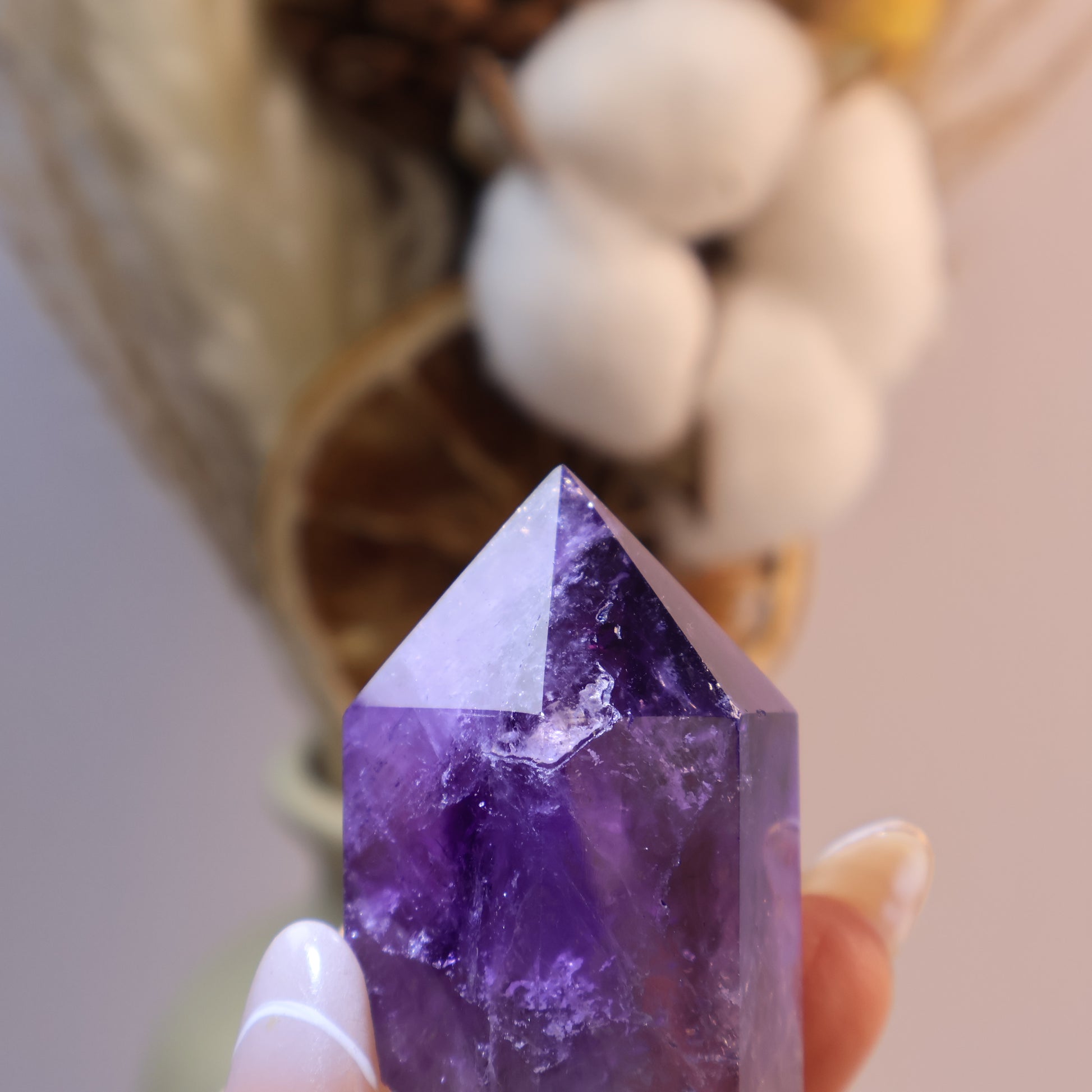 Close-up of Amethyst tower held in hand, shiny crystal peak.