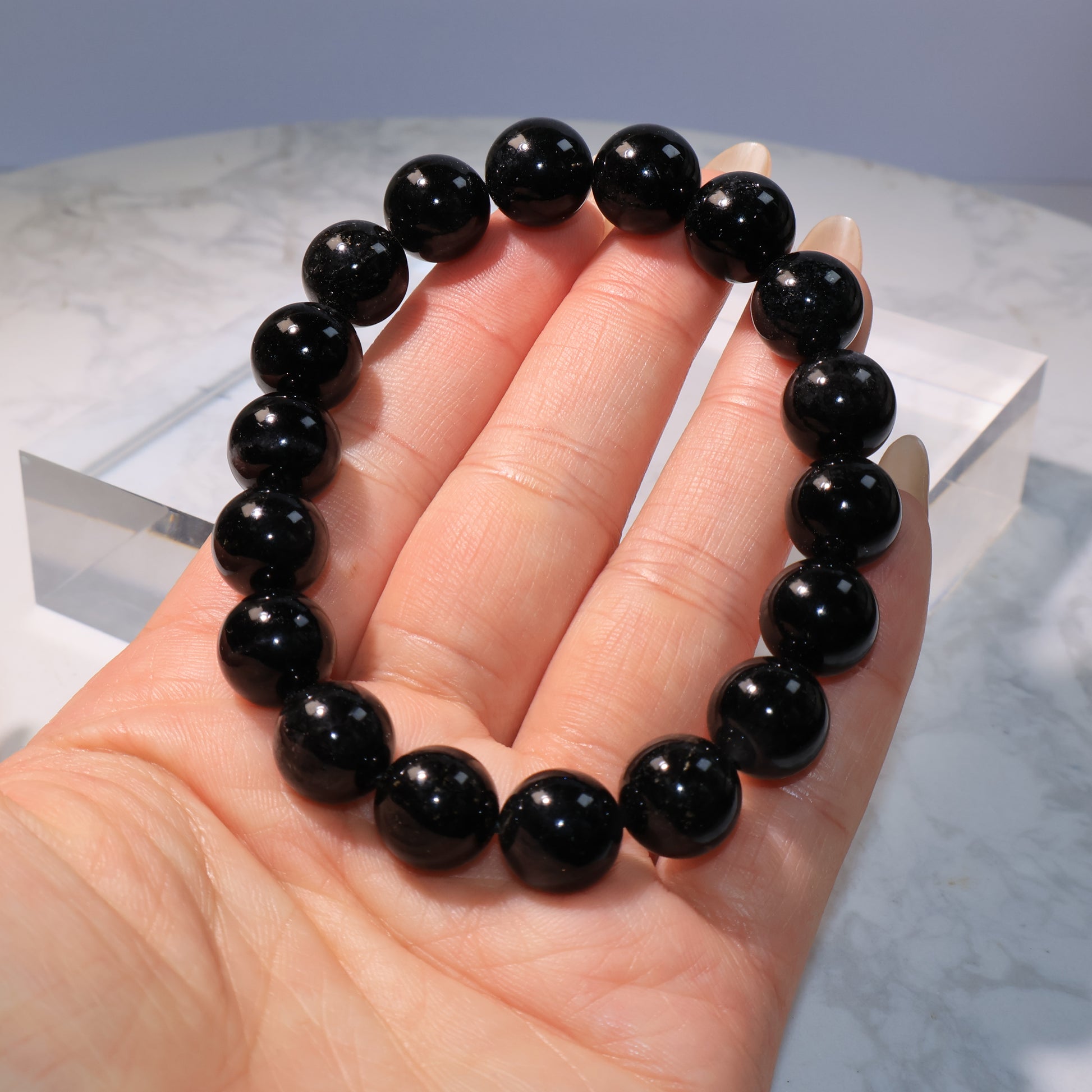 Black Rutilated Quartz Bracelet – close-up view on hand showing glossy beads.