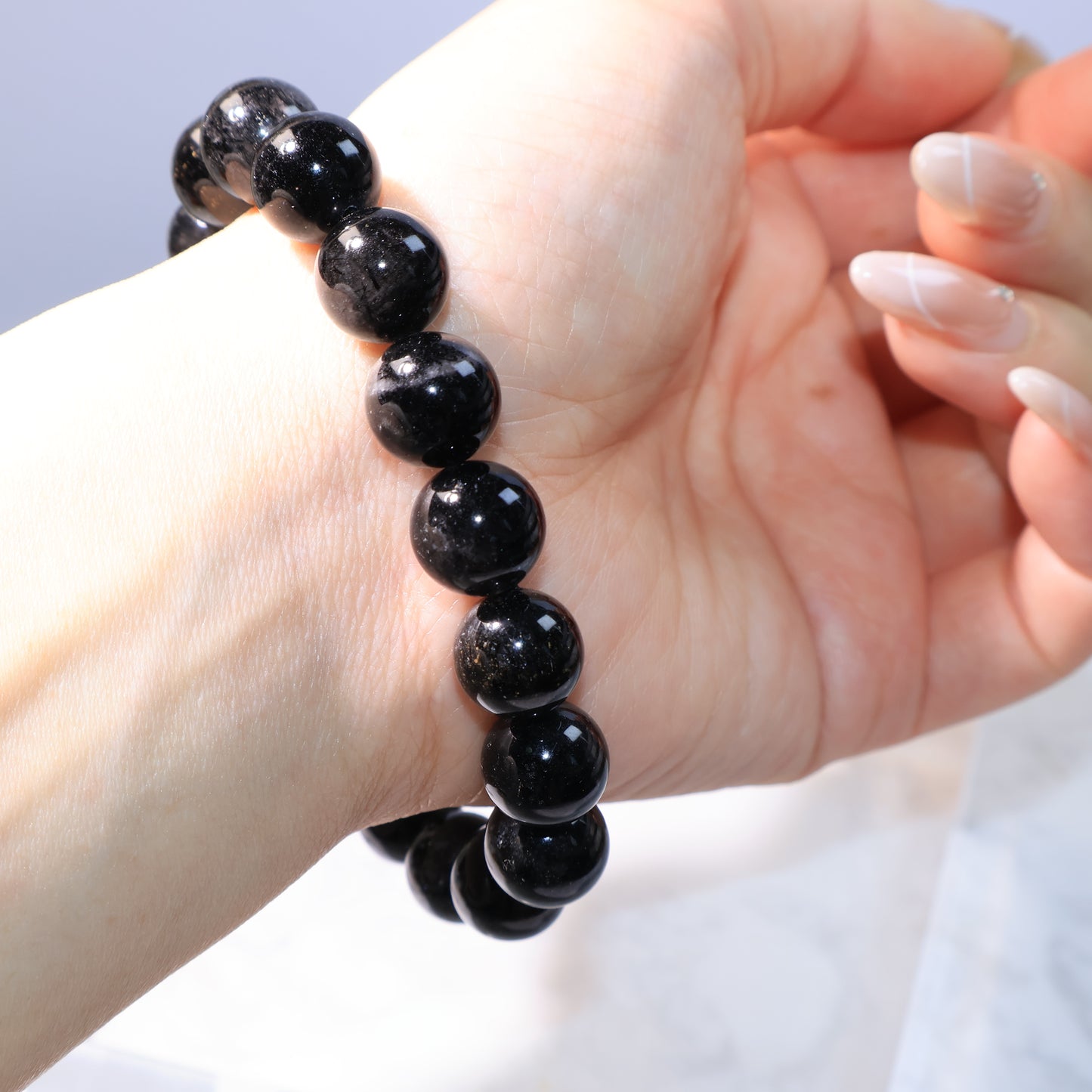 Black Rutilated Quartz Bracelet – side view worn on hand under soft lighting.