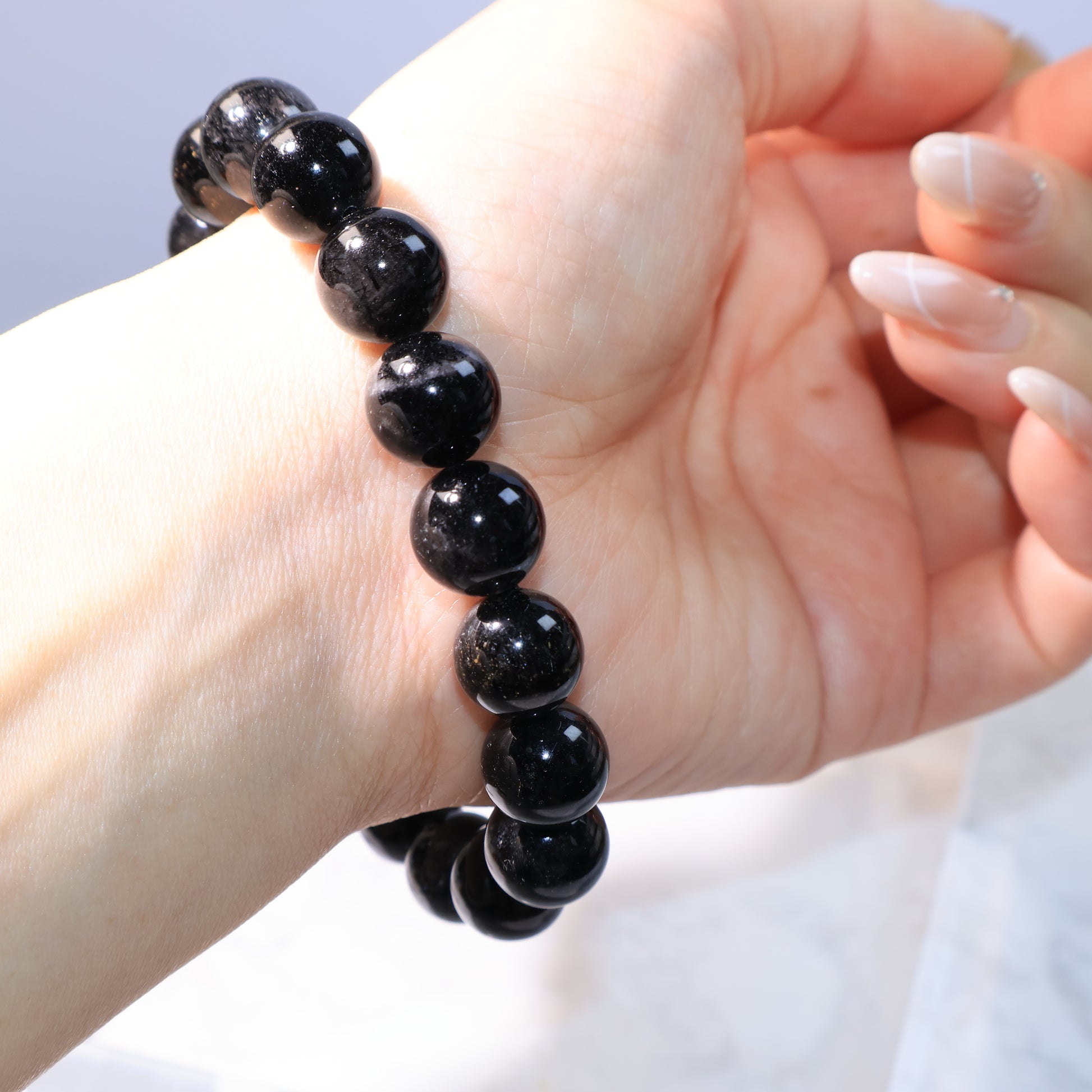 Black Rutilated Quartz Bracelet – side view worn on hand under soft lighting.