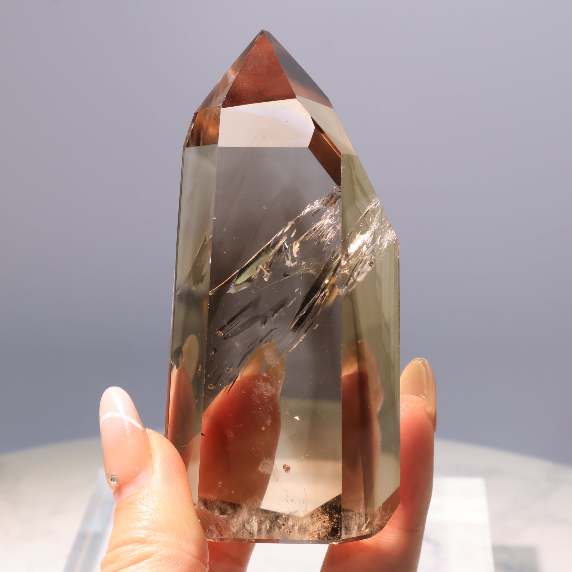Smoky Quartz Tower – handheld view showing clarity with internal fractures and cotton inclusions at the base.