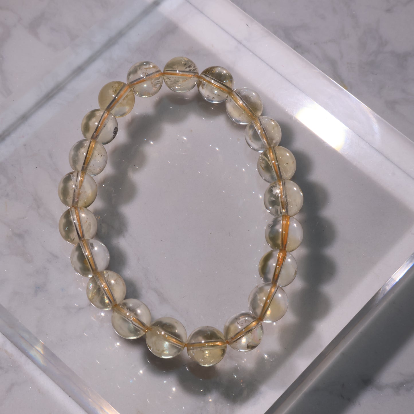 Citrine bracelet with 9mm beads in soft golden tones, displayed on marble background.