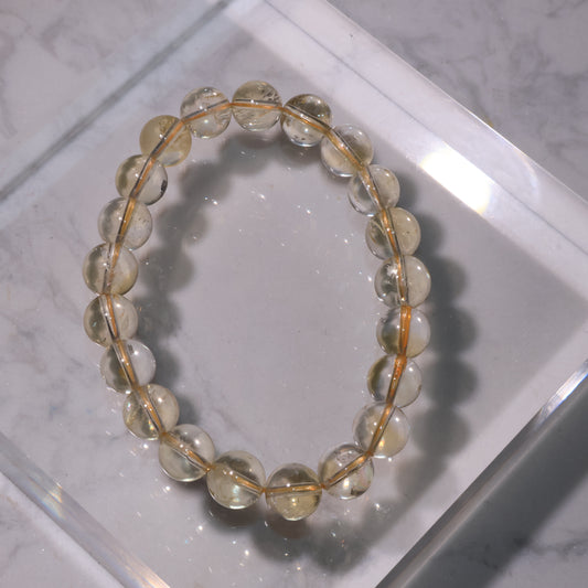 Citrine bracelet with 9mm beads in soft golden tones, displayed on marble background.