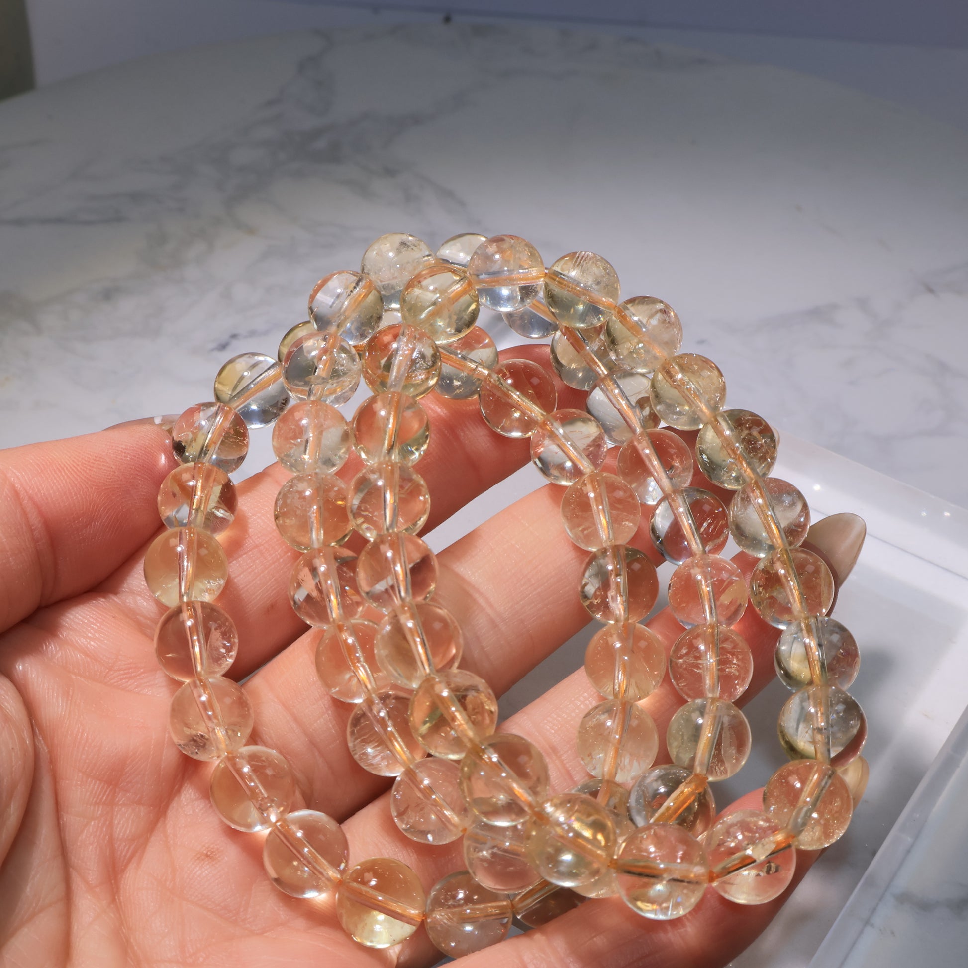 Multiple citrine bracelets displayed together, highlighting soft golden tones and rainbow flashes.