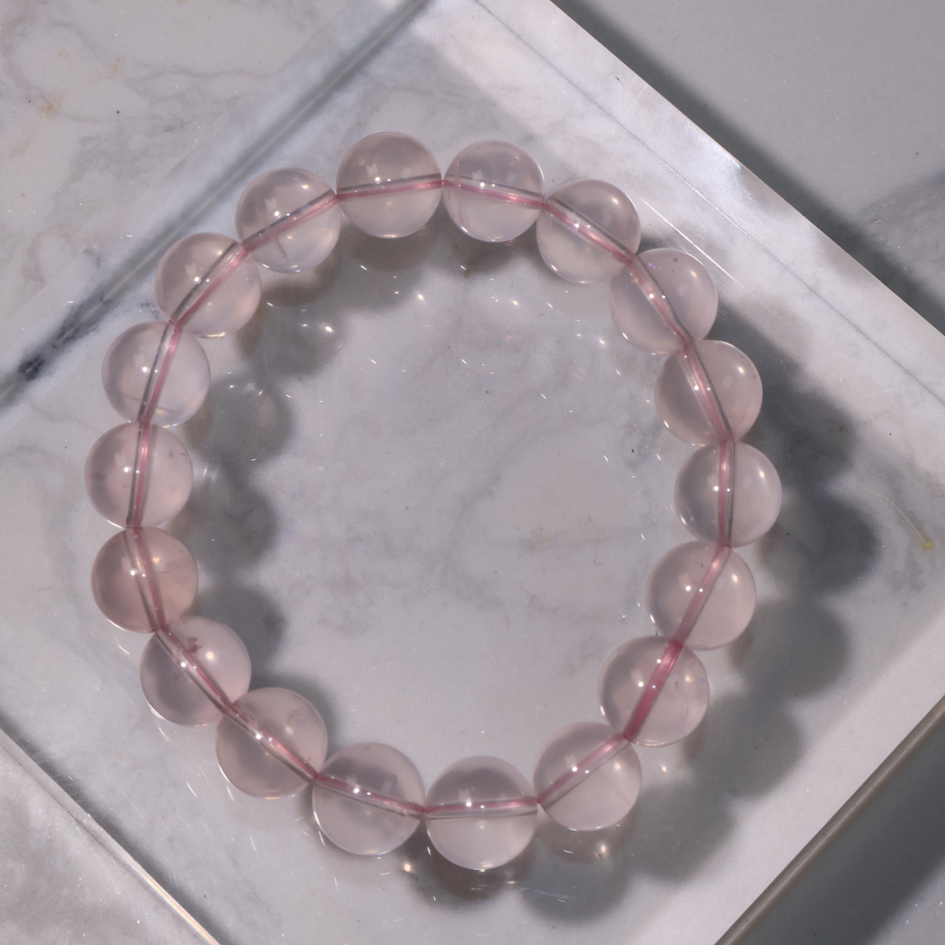 Starlight Rose Quartz bracelet on marble surface, showing soft pink transparency.