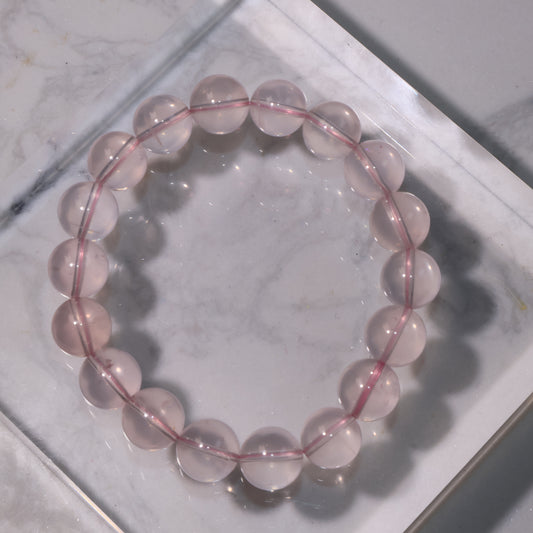Starlight Rose Quartz bracelet on marble surface, showing soft pink transparency.