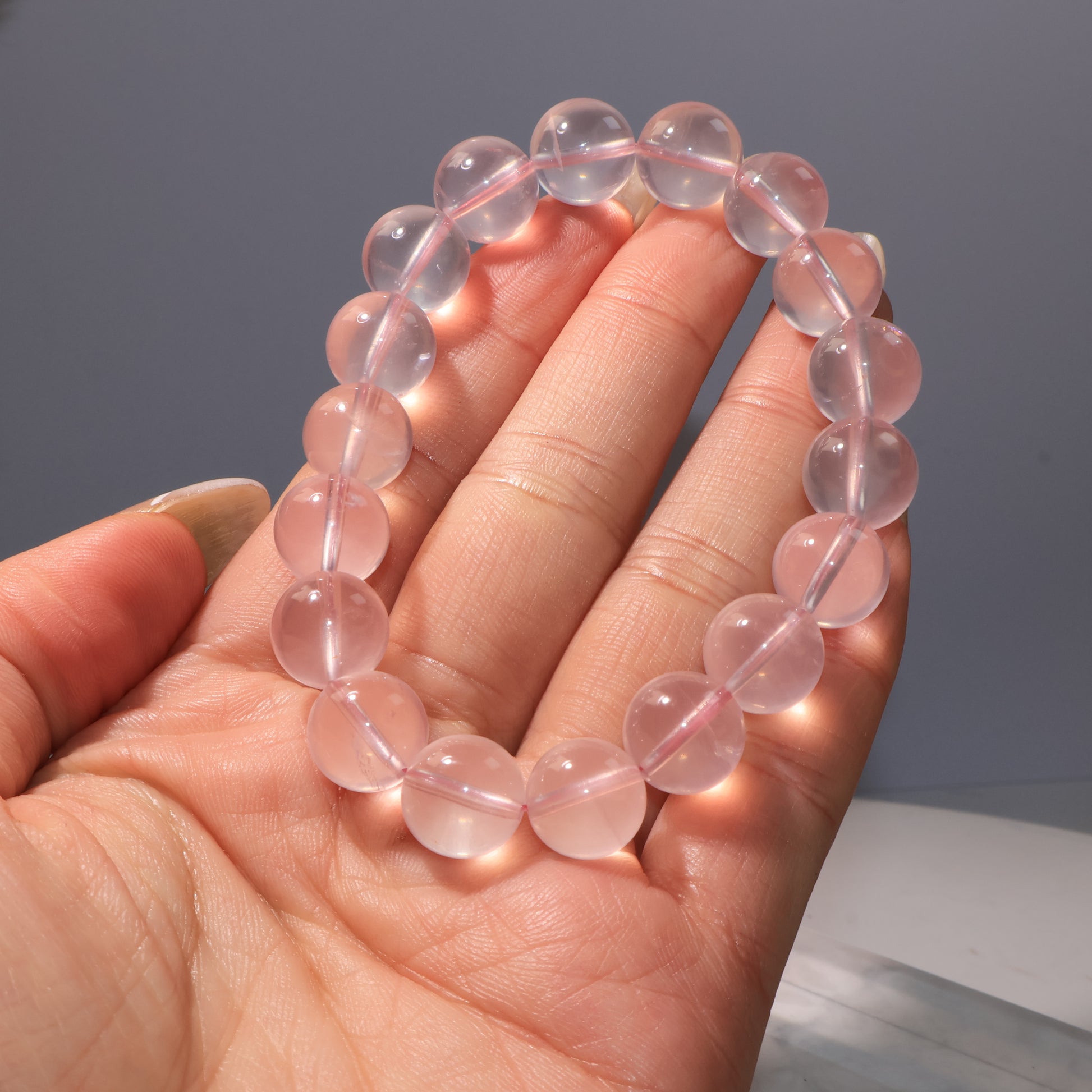 Bracelet on palm, beads glowing under light, with slight natural inclusions.