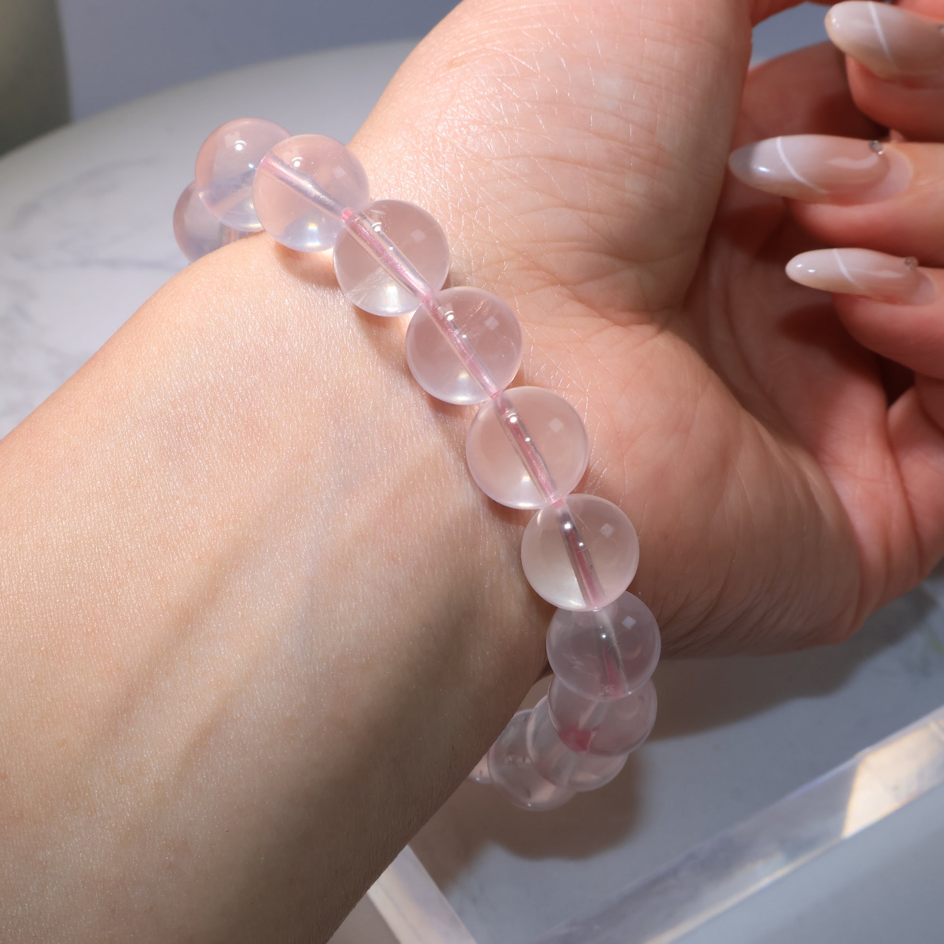 Rose Quartz bracelet worn on wrist, beads shining with a translucent pink glow.