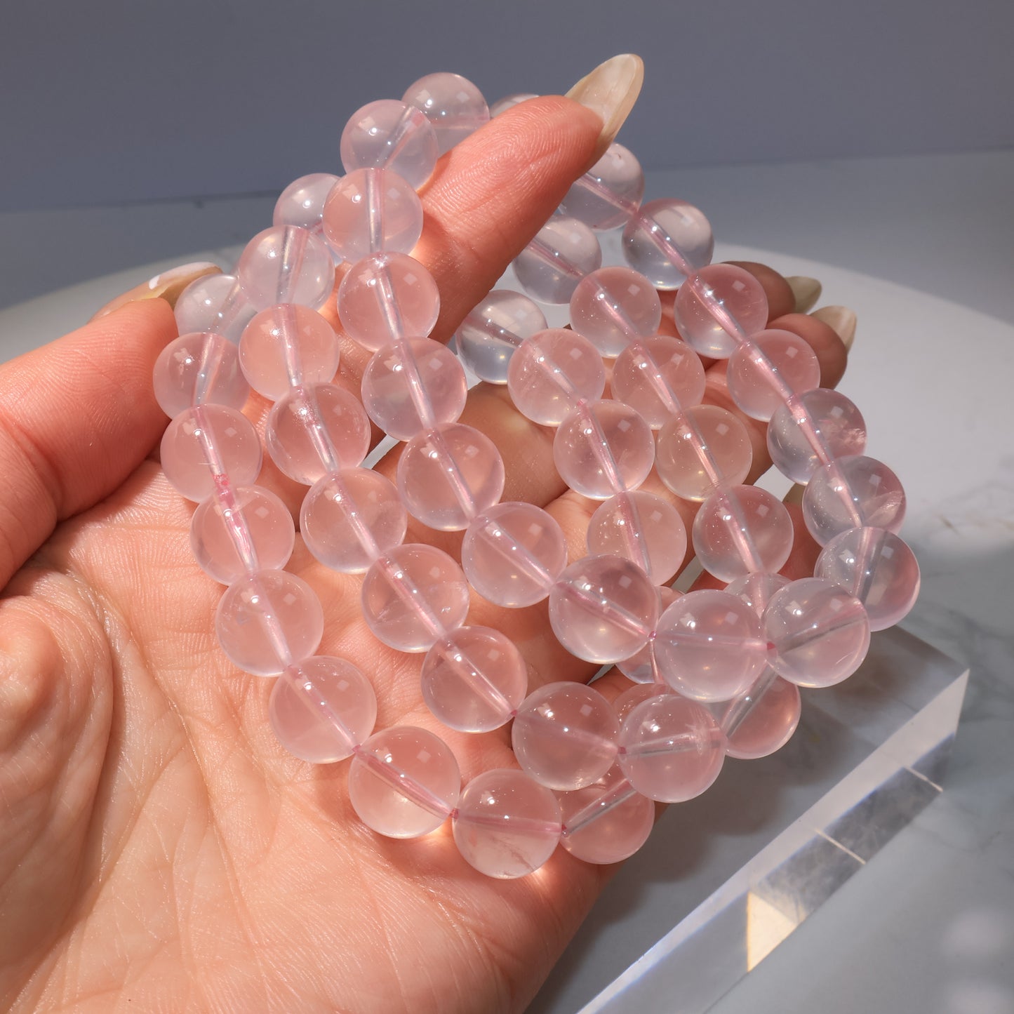 Multiple Rose Quartz bracelets stacked together on hand, creating a full pink aura.