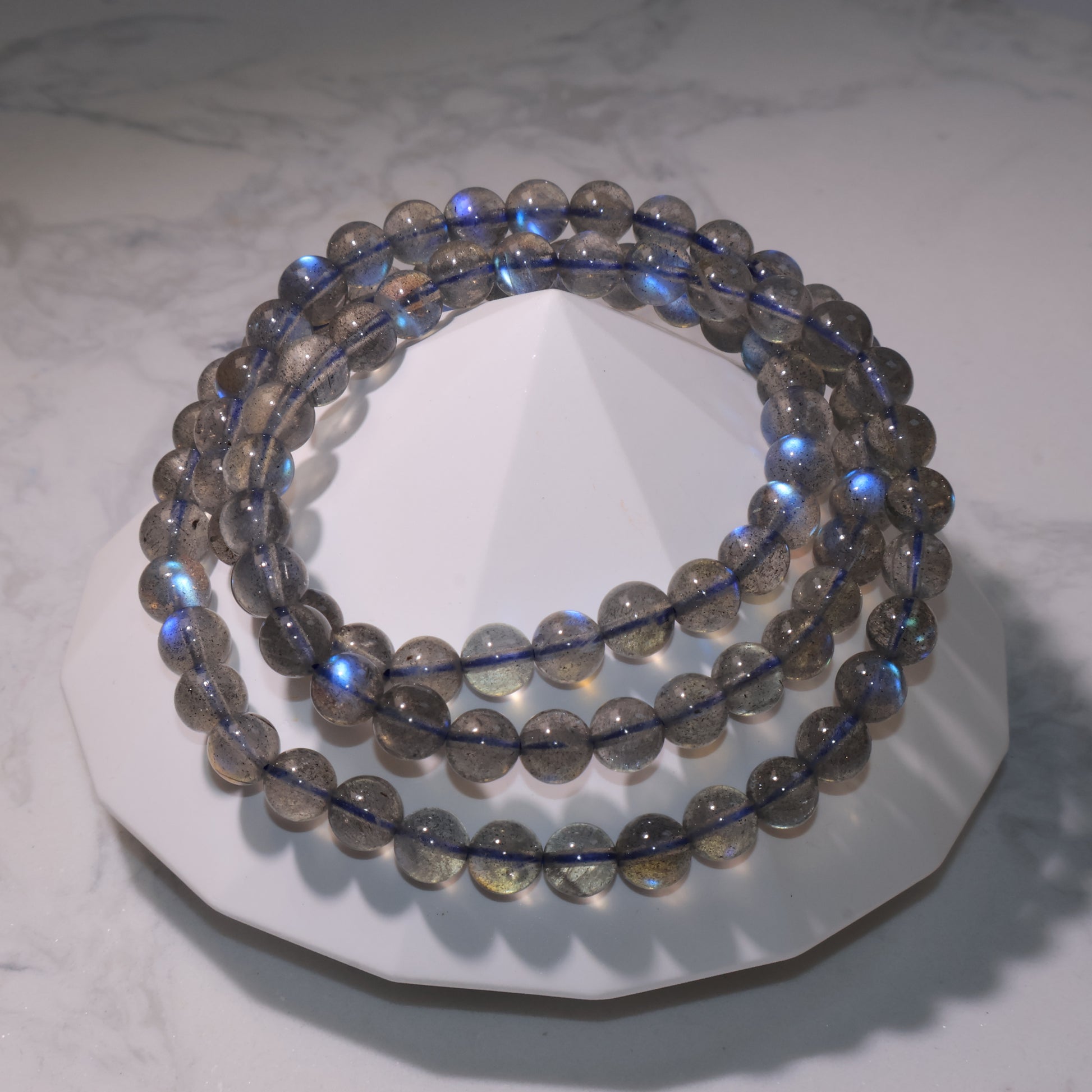Labradorite bracelet with strong blue flashes on white stand｜白色底座上的拉長石手串，透度佳藍光強烈