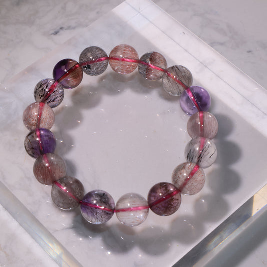 Super Seven bracelet on clear display stand, showing light yet transparent beads｜透明展示座上的超七手串，顏色淡雅但晶體透亮