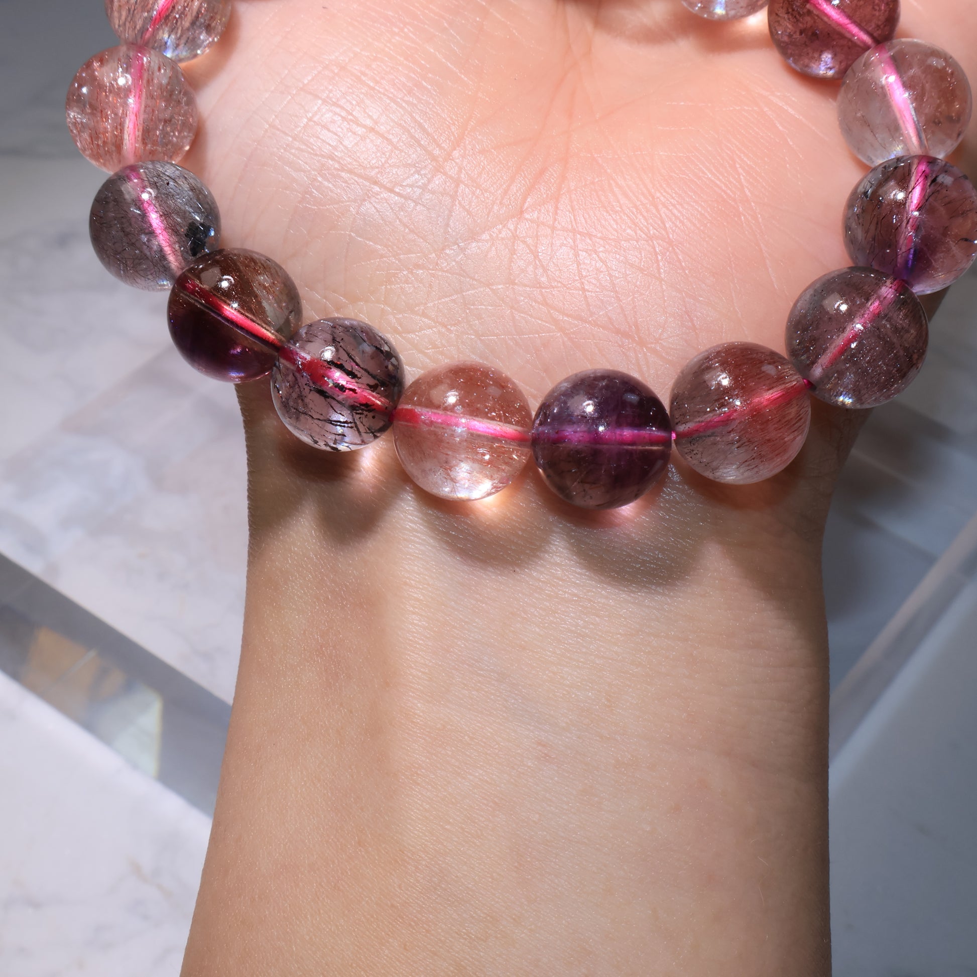 Wrist shot of bracelet showing soft purple and red hues｜佩戴於手腕，展現淡紫與紅色調