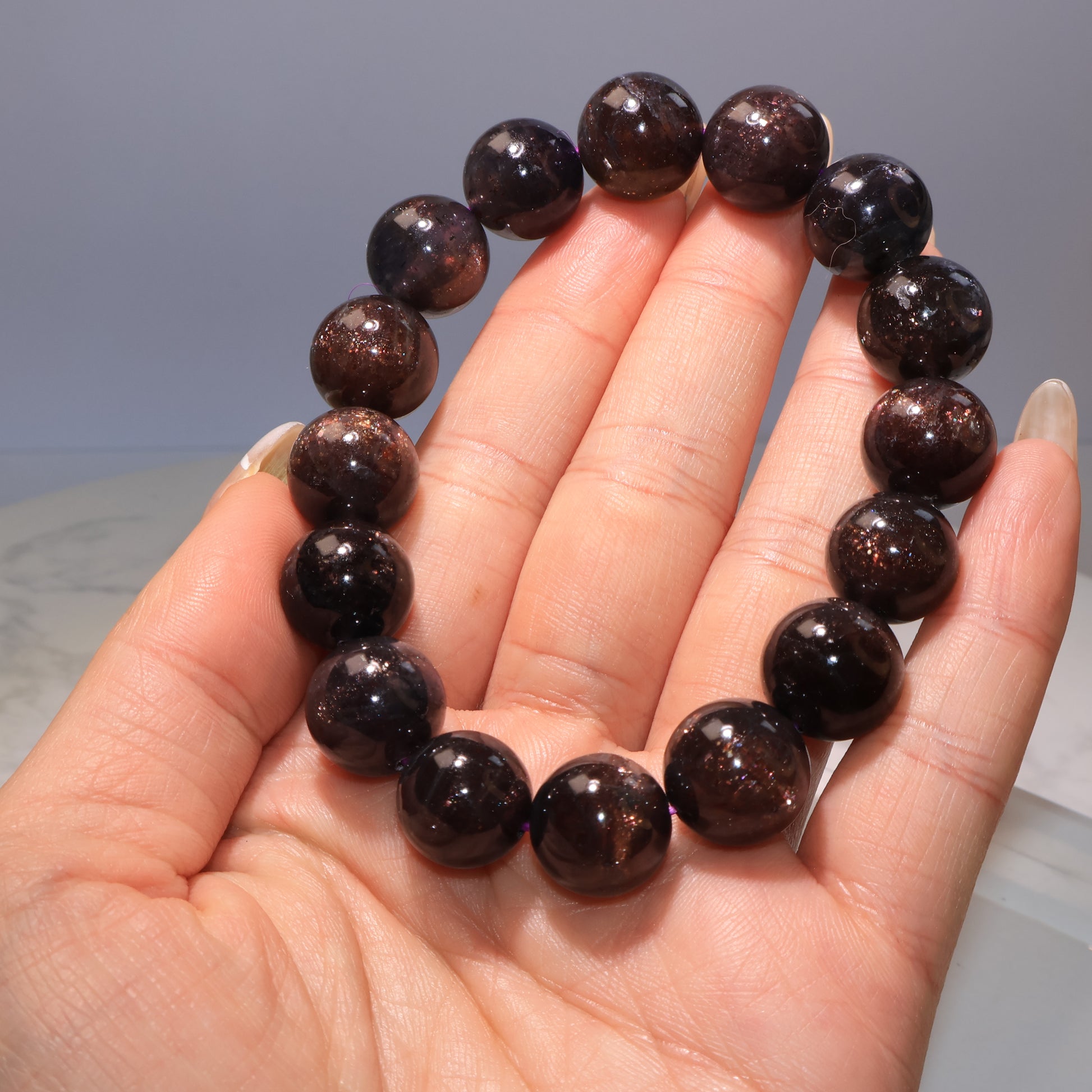 Bracelet held in hand with visible mica sparkles｜手持血滴堇青手串，可見晶體中閃爍雲母