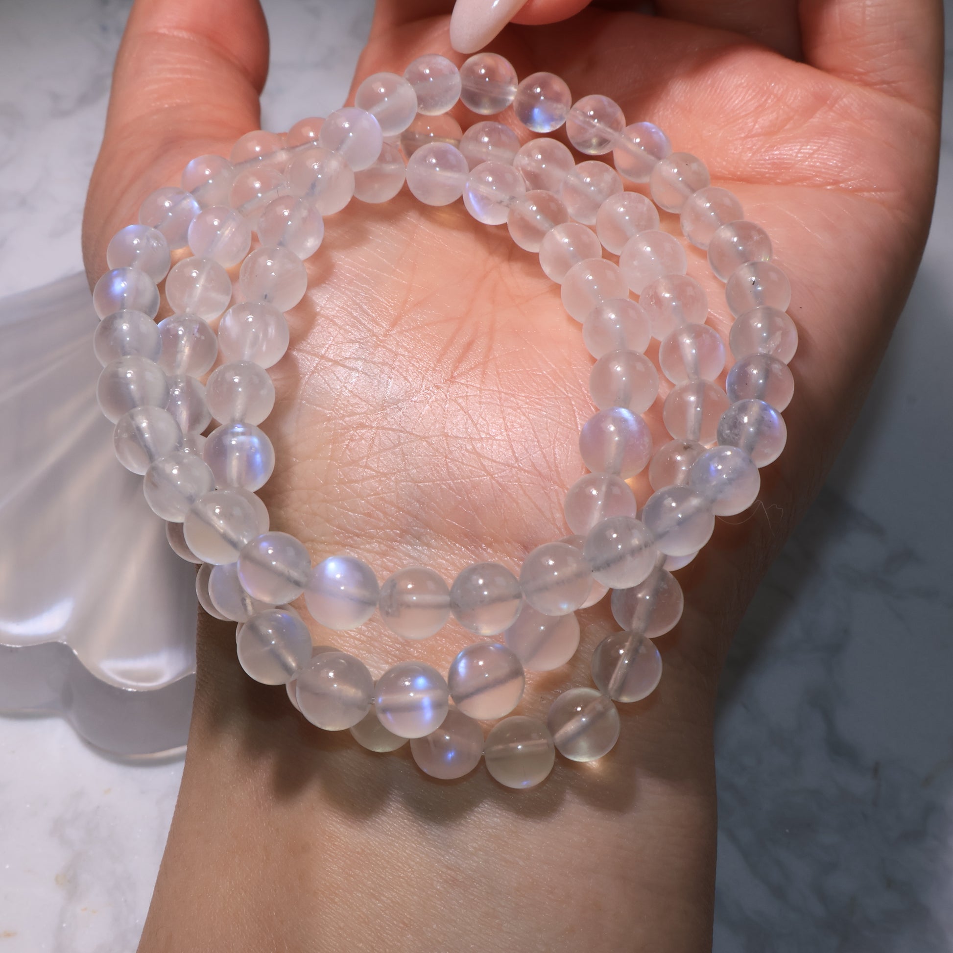Moonstone bracelet wrapped on the wrist, showing multiple layers with dreamy blue reflections.