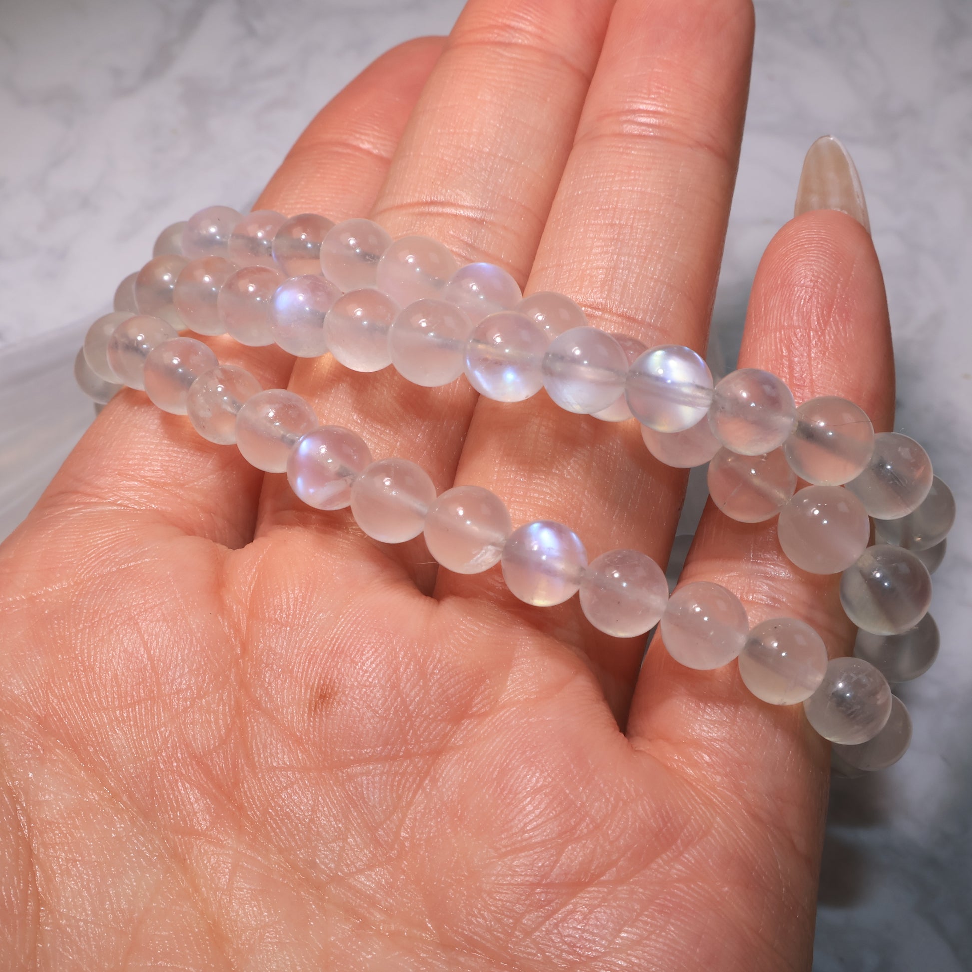 Handheld Moonstone bracelet in soft lighting, emphasizing the gentle glow of the beads.