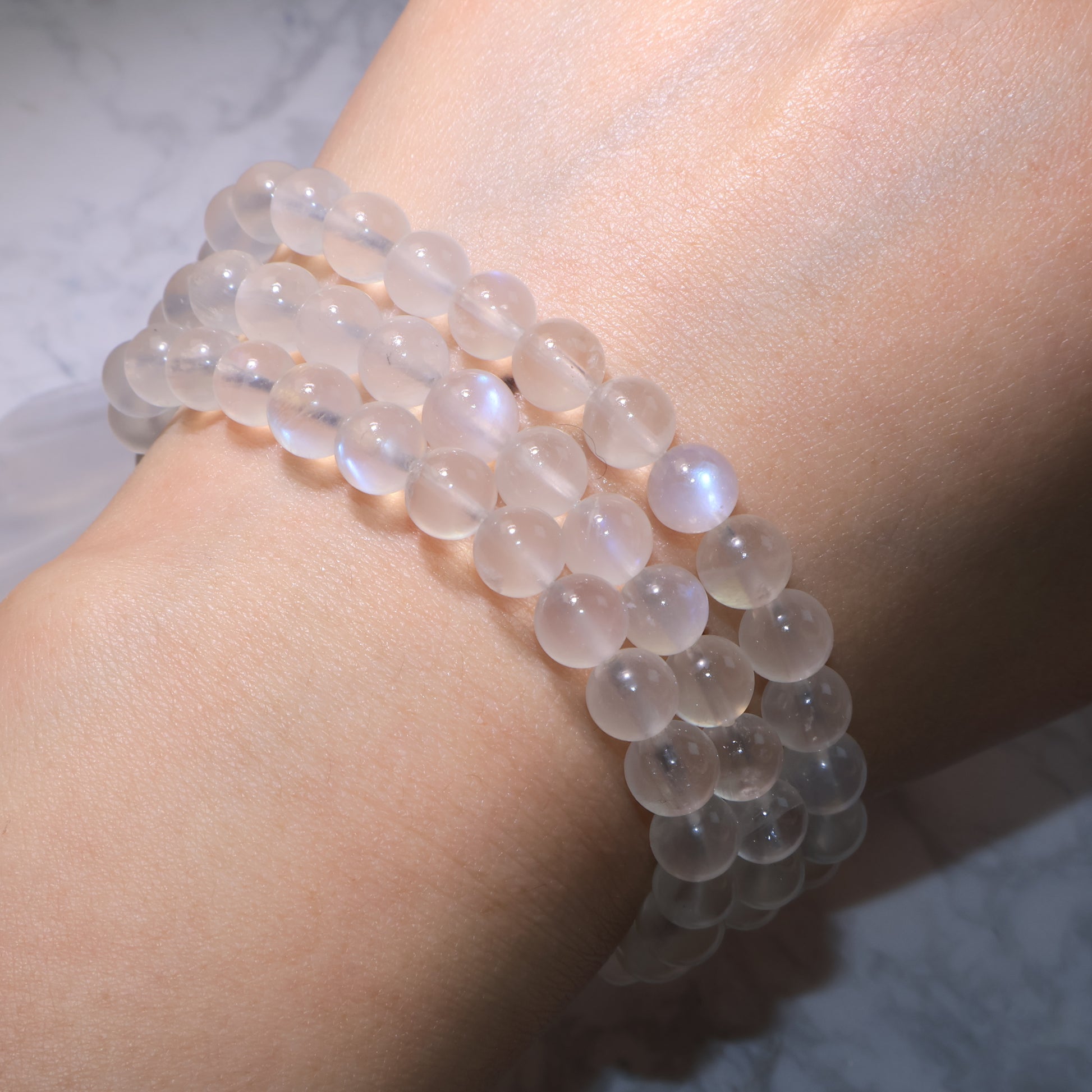 Triple-wrap Moonstone bracelet draped on the wrist, showing natural iridescent flashes.
