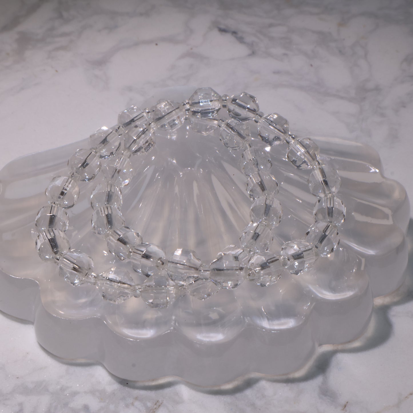 Clear Quartz bracelet (7mm, 15.5cm) displayed on a crystal dish with bright clarity.