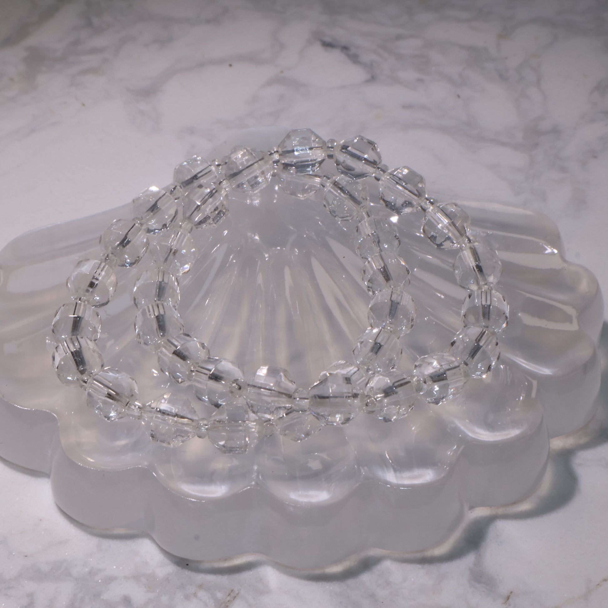 Clear Quartz bracelet (7mm, 15.5cm) displayed on a crystal dish with bright clarity.