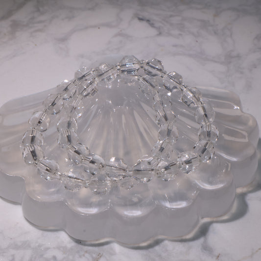 Clear Quartz bracelet (7mm, 15.5cm) displayed on a crystal dish with bright clarity.