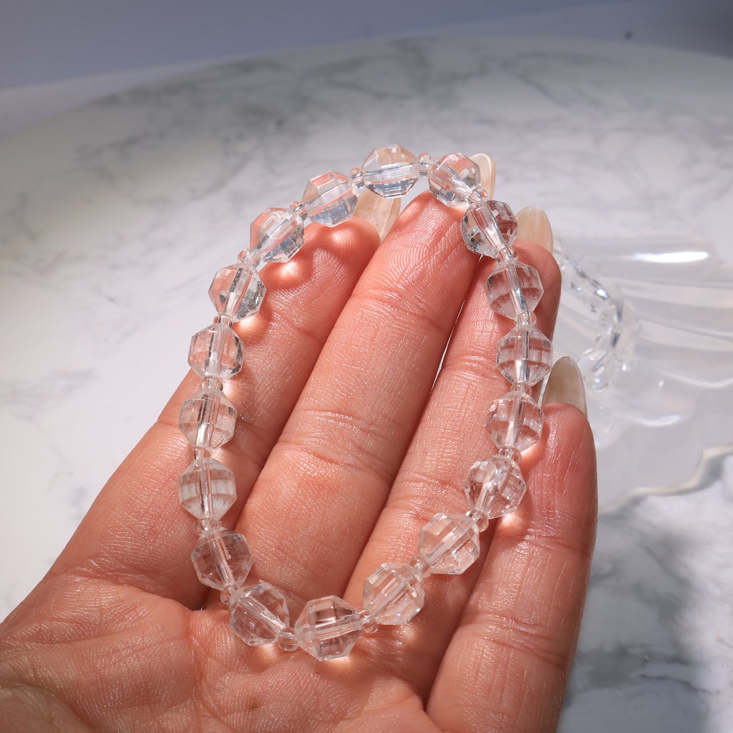 Handheld view of the faceted Clear Quartz bracelet, showing sparkling transparency.