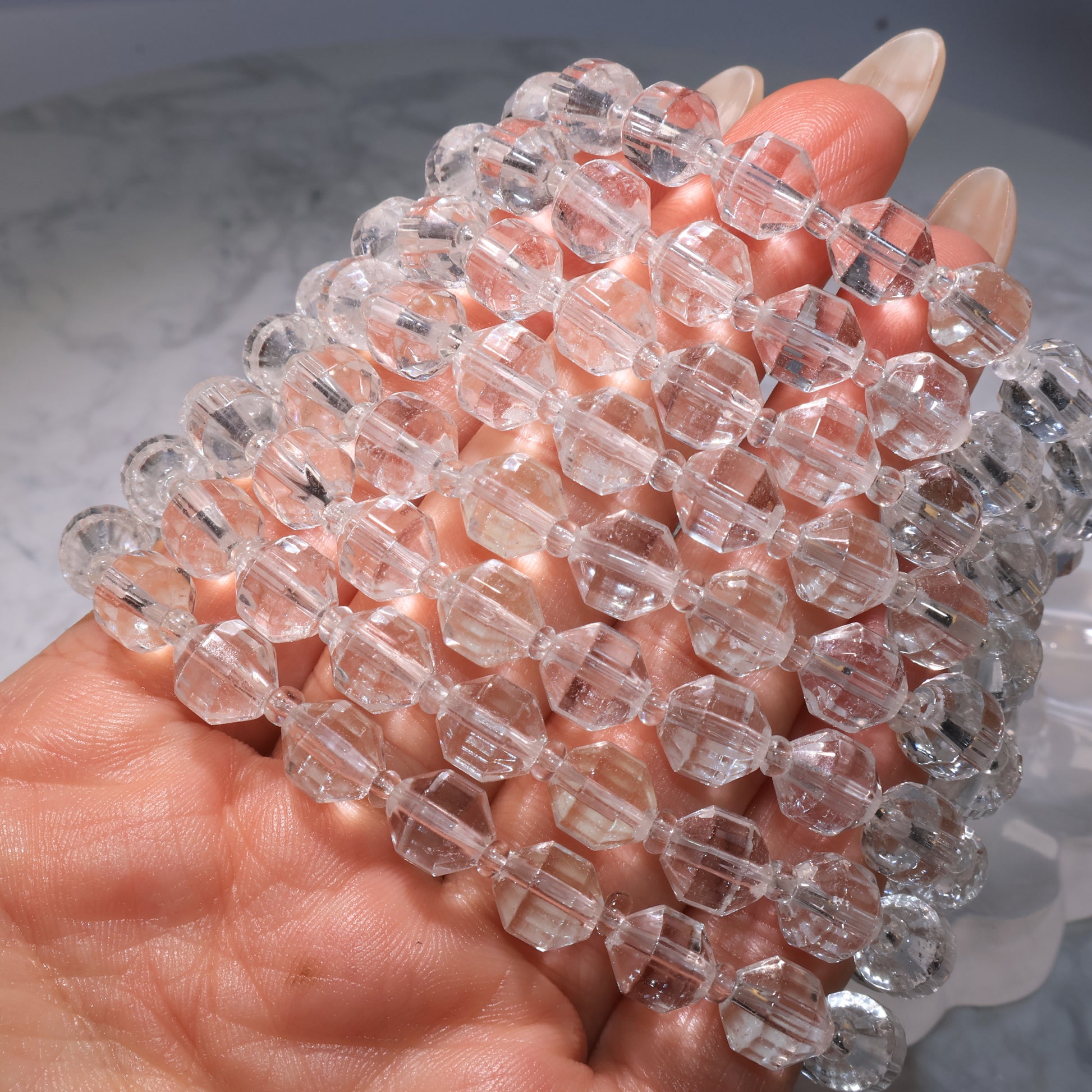 Multiple Clear Quartz bracelets stacked together, reflecting brilliant light.